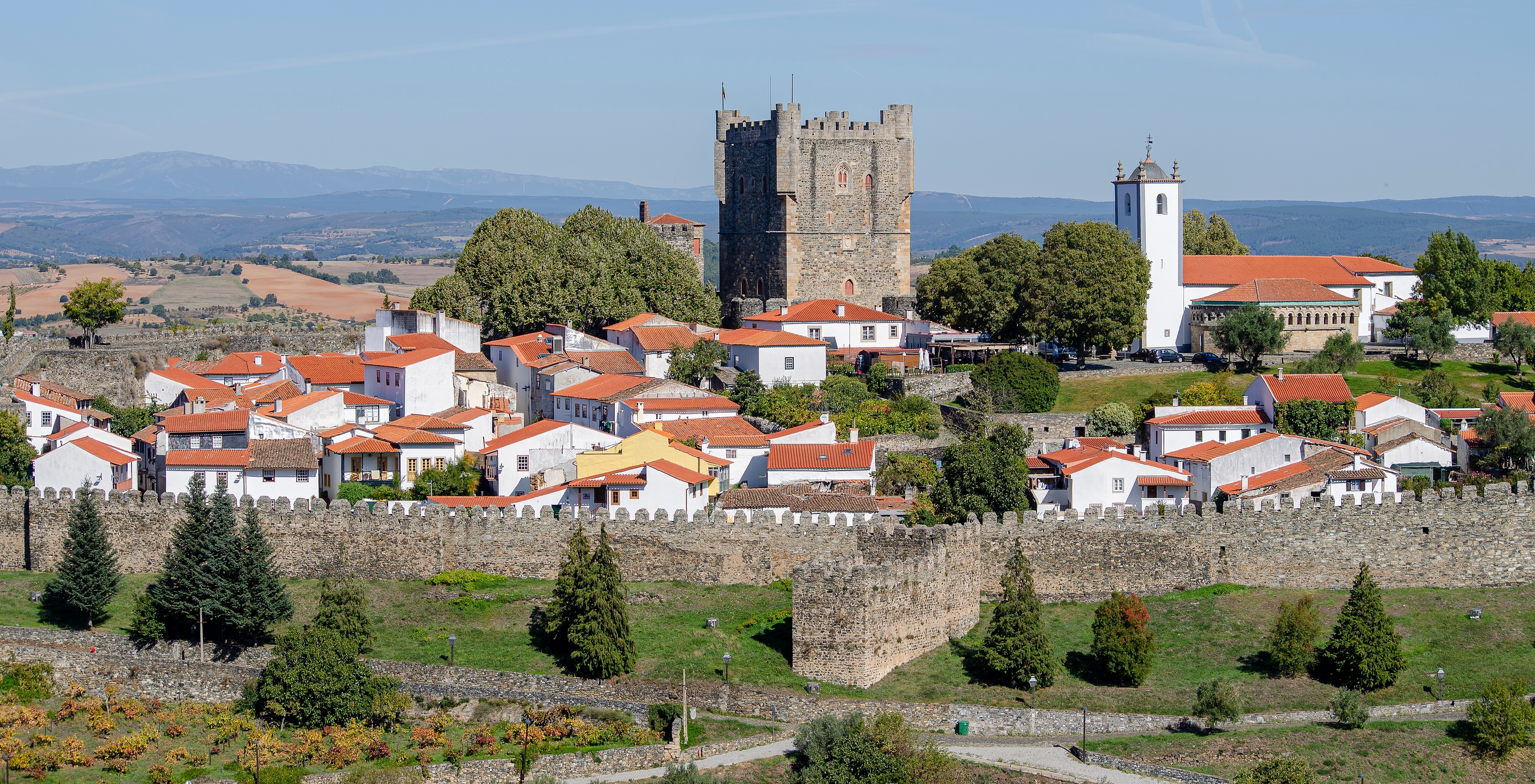 View of Bragança Castle with white houses with red roofs inside the walls and gardens outside