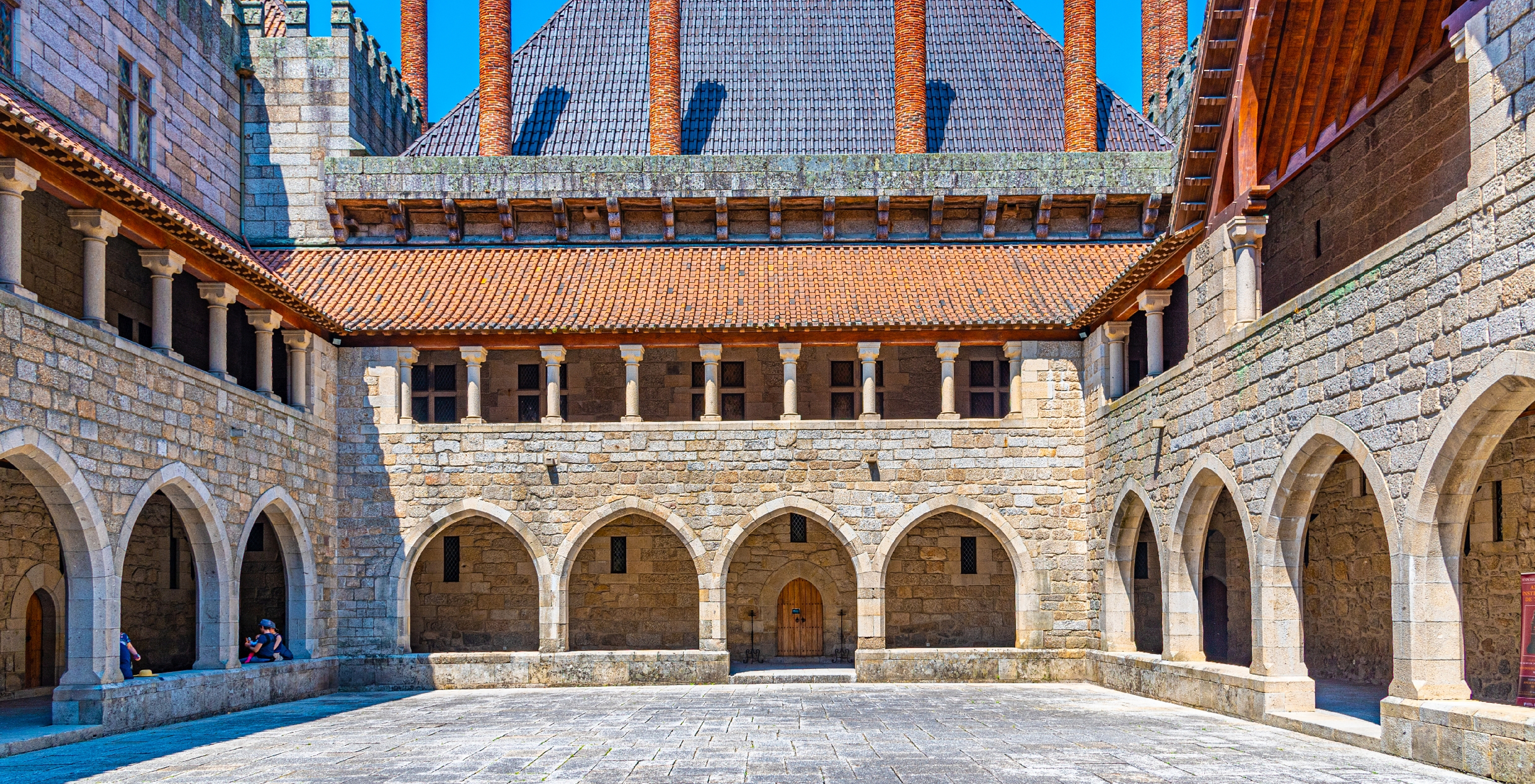 View of the inner courtyard of the Palace of the Dukes of Braganza, with stone walls, arches, and chimneys