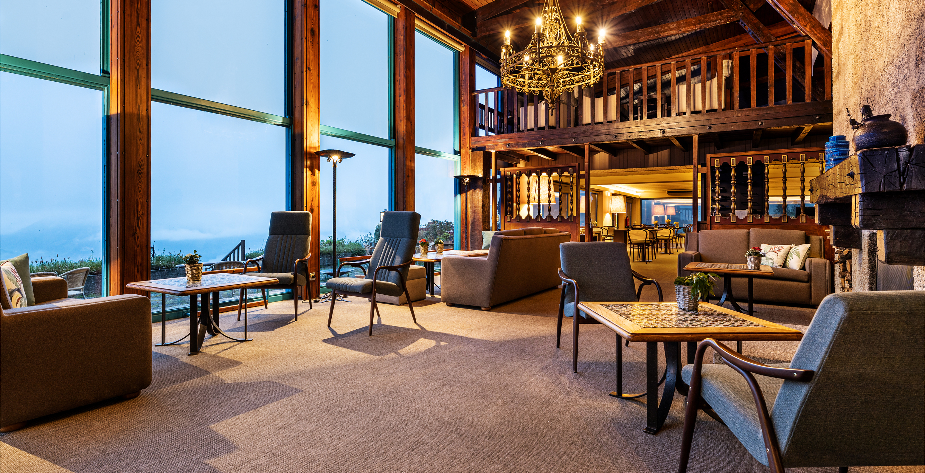 Hotel bar in Peneda-Gerês National Park, with several tables and sofas, with a large window overlooking the mountain