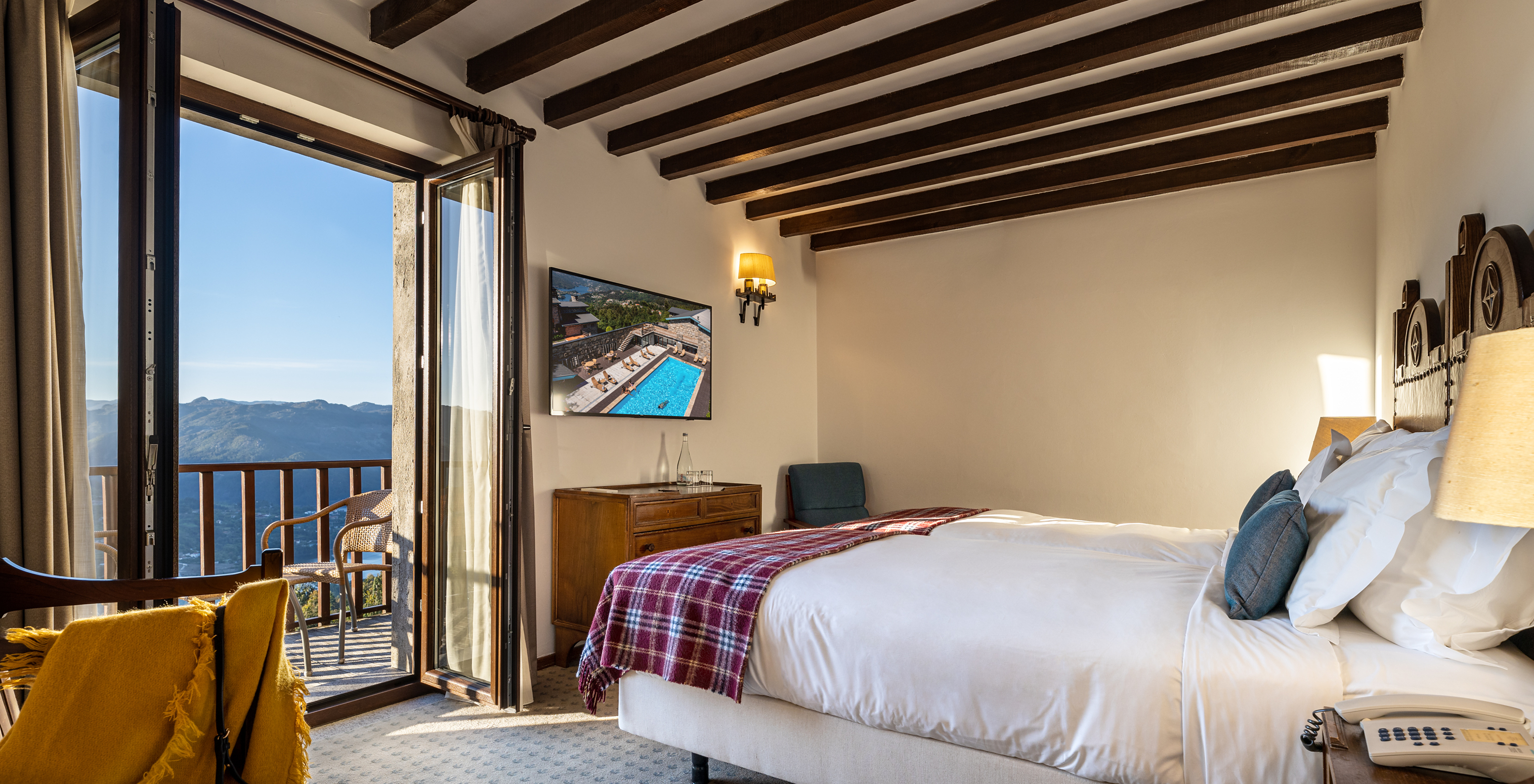The Superior Balcony Room of the Pousada Caniçada - Gerês has a bed, bedside table, television, and a balcony with a view
