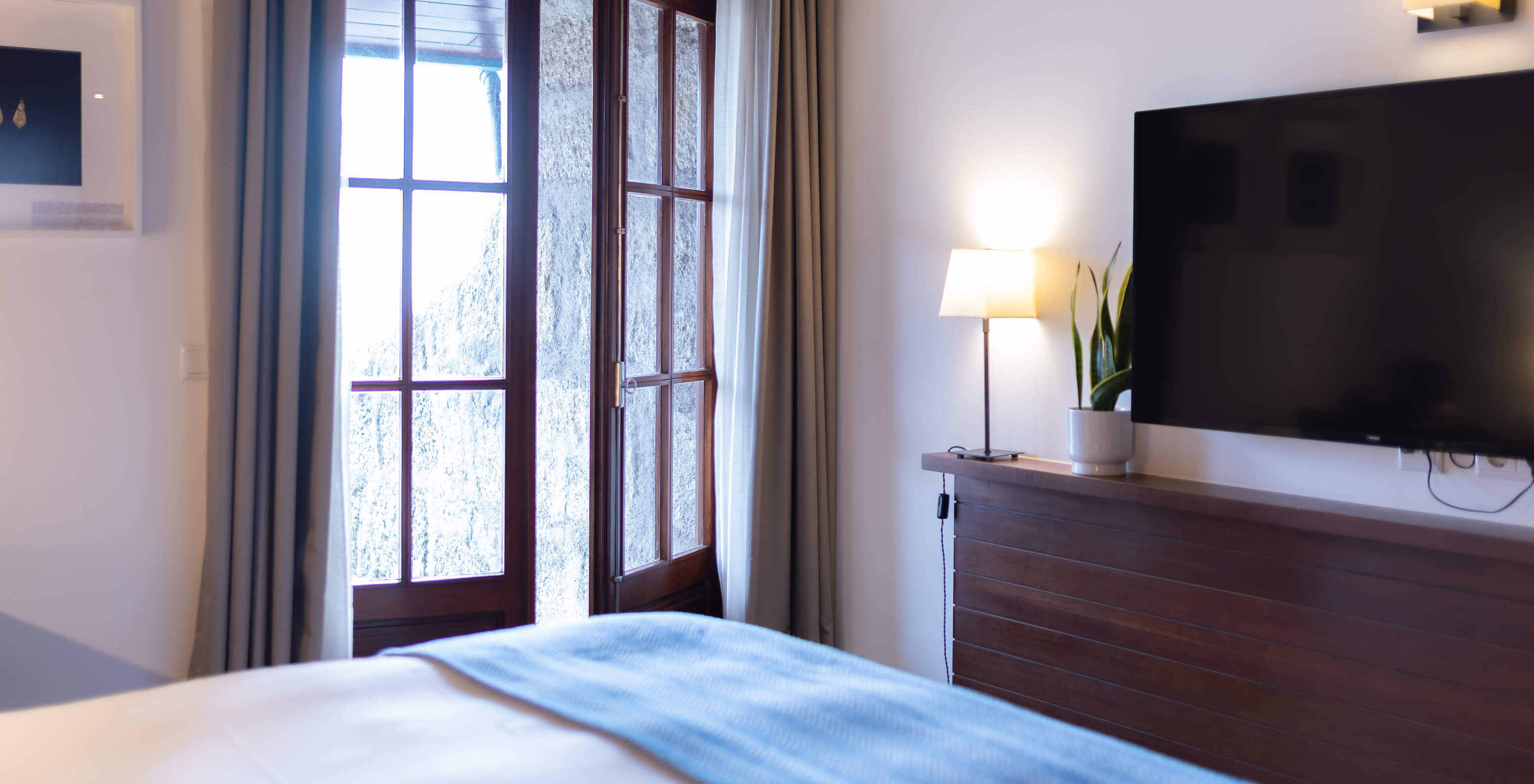 The Superior Balcony Room at Pousada Caniçada - Gerês has a bed with a TV and a window with a view of the Serra do Gerês
