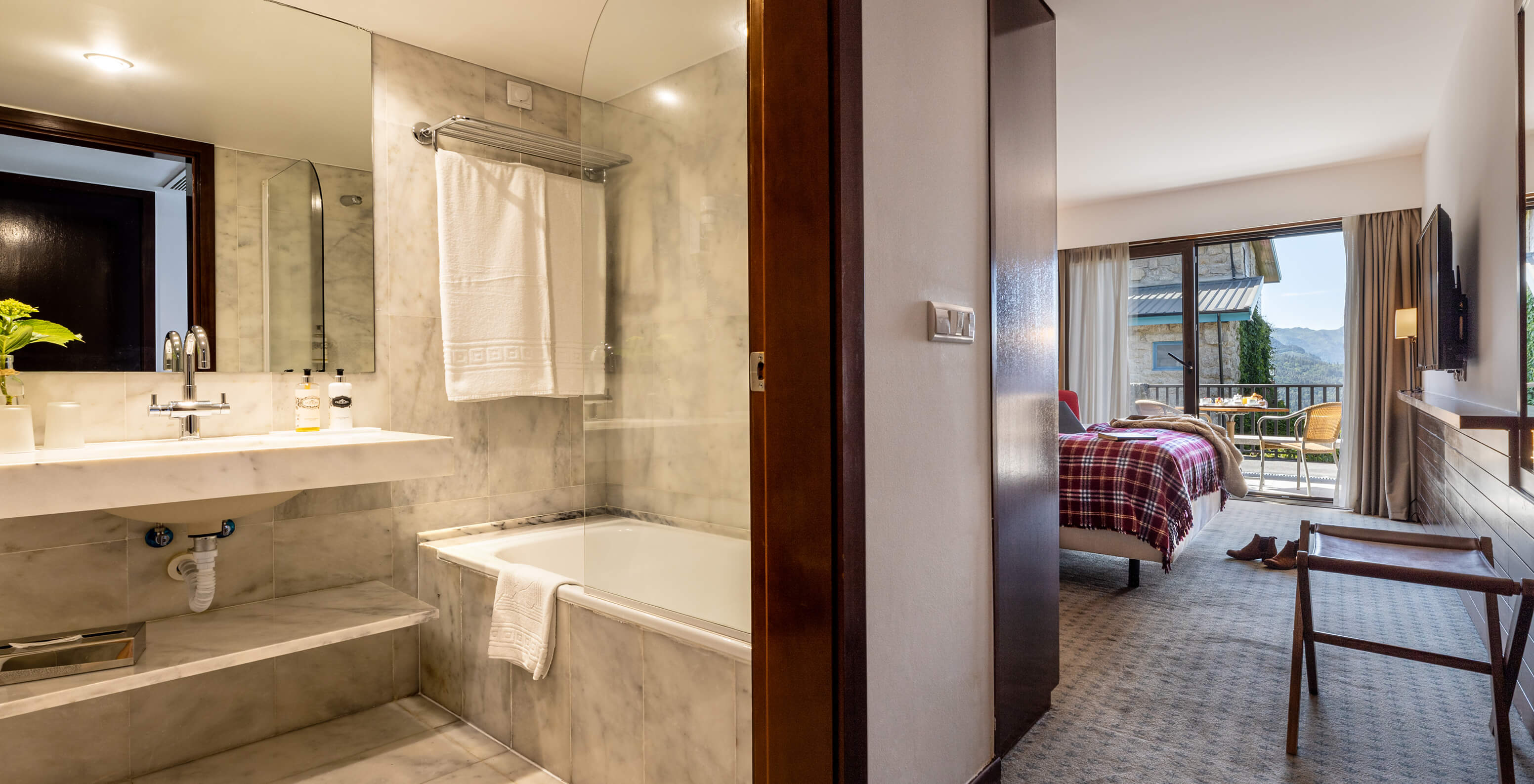 The Superior Terrace Room at Pousada Caniçada - Gerês has a bathroom with a bathtub and sink and a room with a balcony
