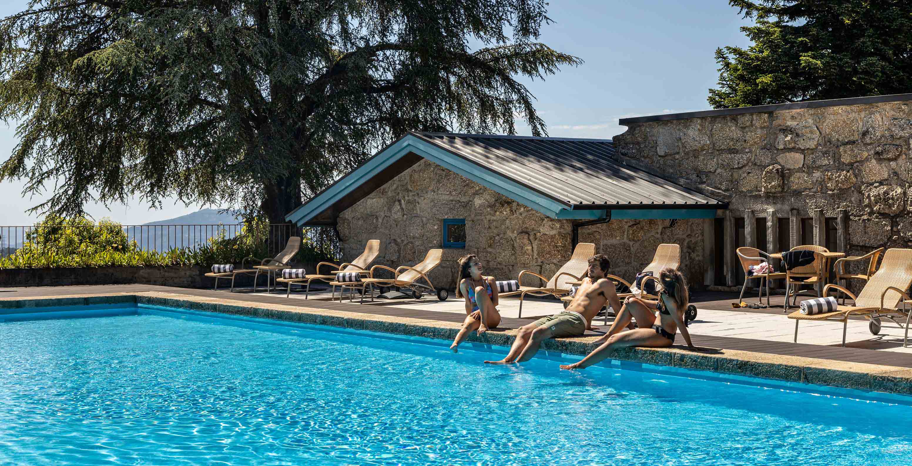 Outdoor pool with sun loungers and stone building of Pousada Caniçada - Gerês, Mountain Hotel in Gerês