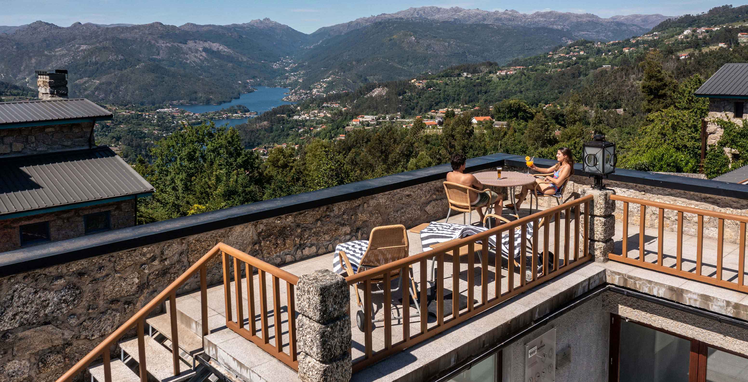 Guests relax at an outdoor table at Pousada Caniçada - Gerês, Mountain Hotel in Gerês, with a view of the river
