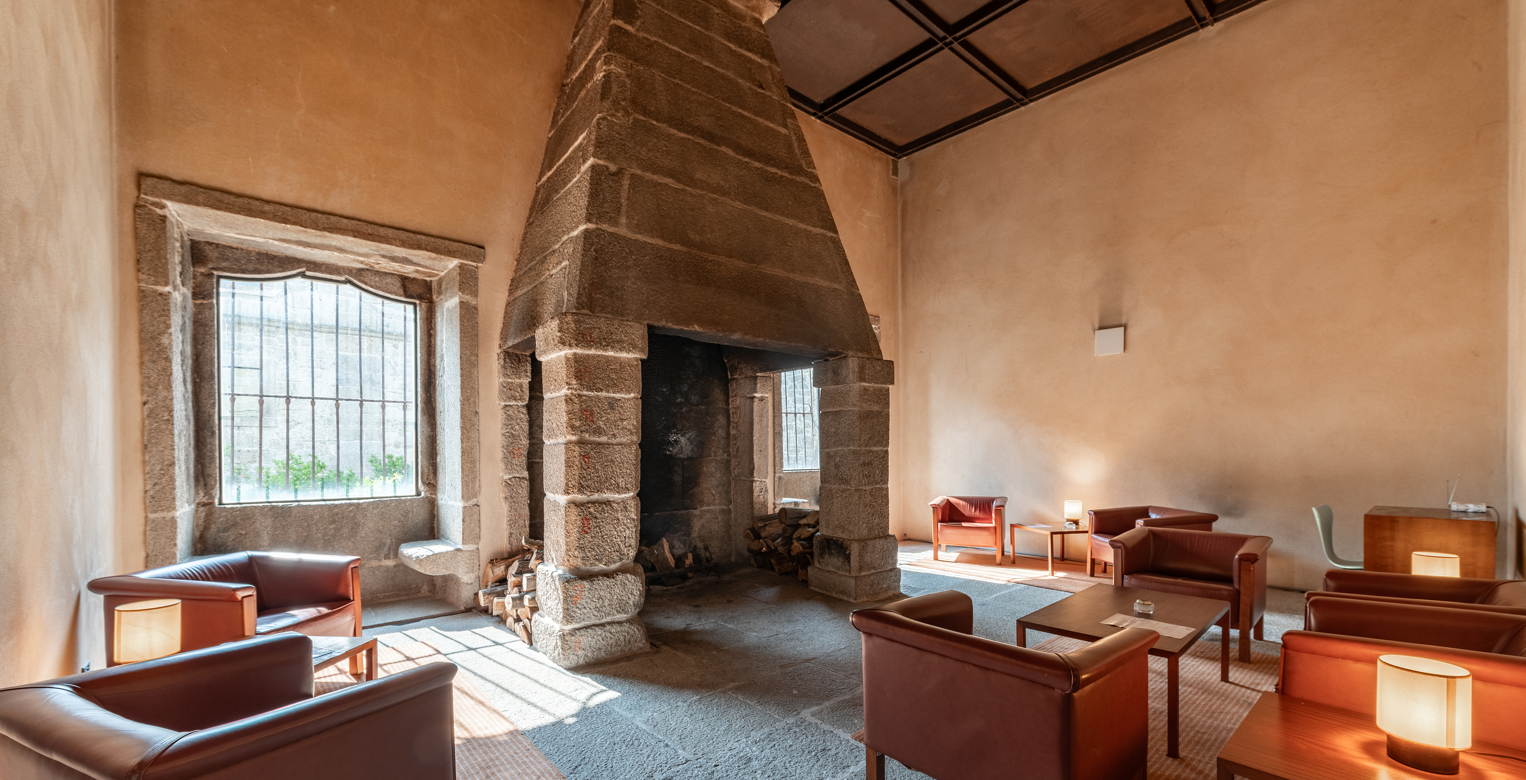 Bar of the Pousada Mosteiro Amares, a historic hotel in Amares, with a stone fireplace and tables with sofas