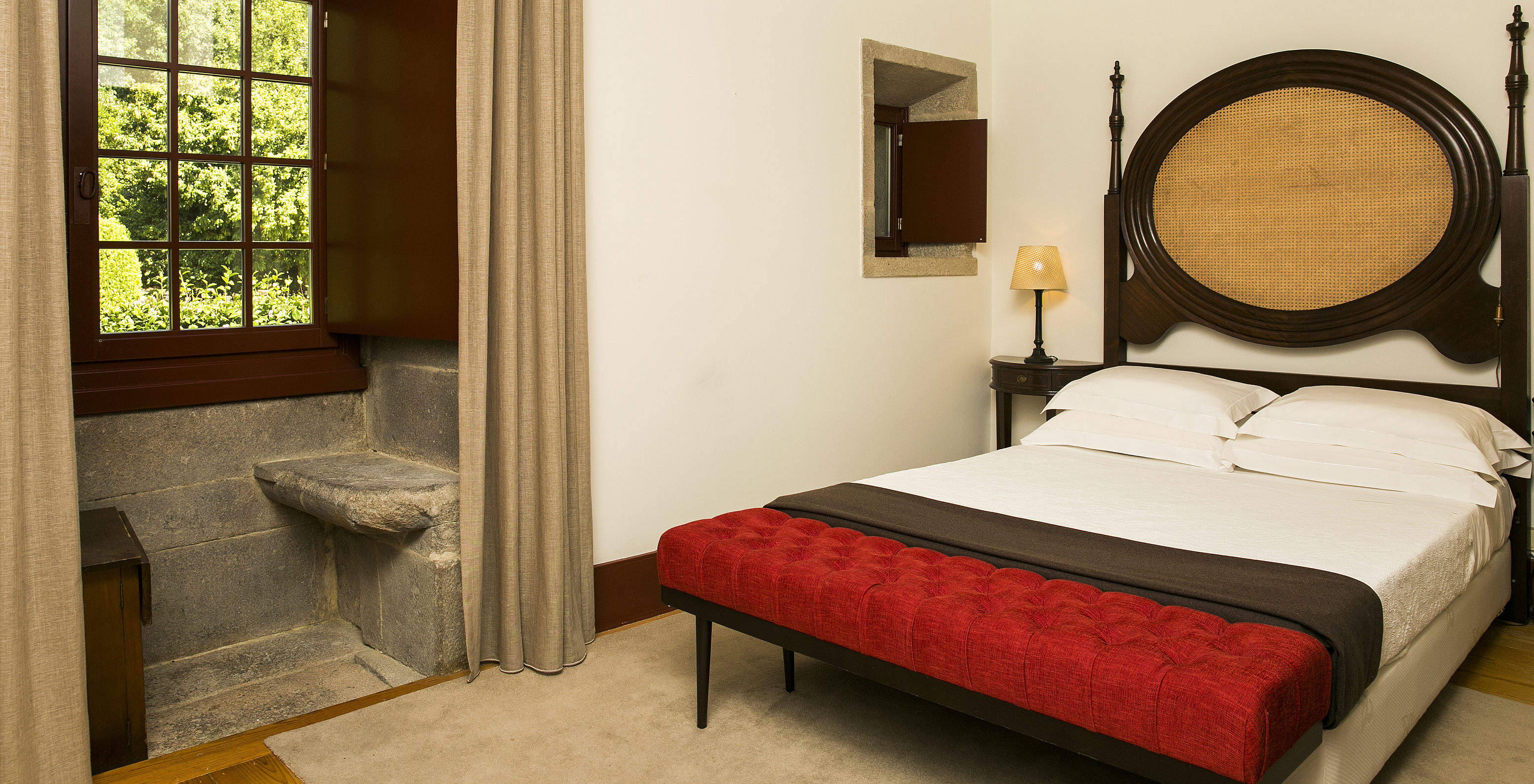 The Classic Room of The Pousada Mosteiro Guimarães has a double bed with a dark wood headboard and a window