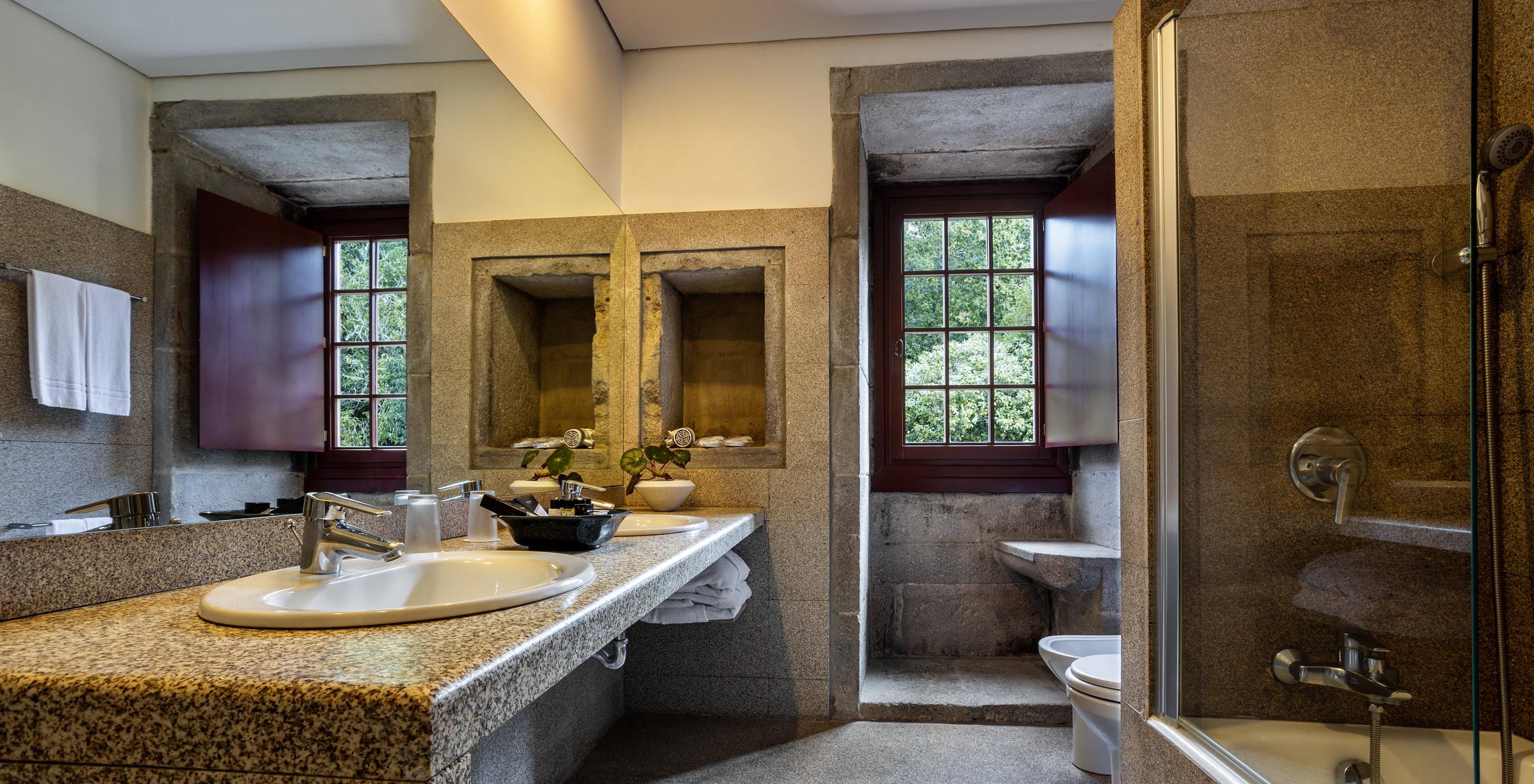 The Standard Suite of The Pousada Mosteiro Guimarães has a bathroom with a sink, window, bathtub, and toilet