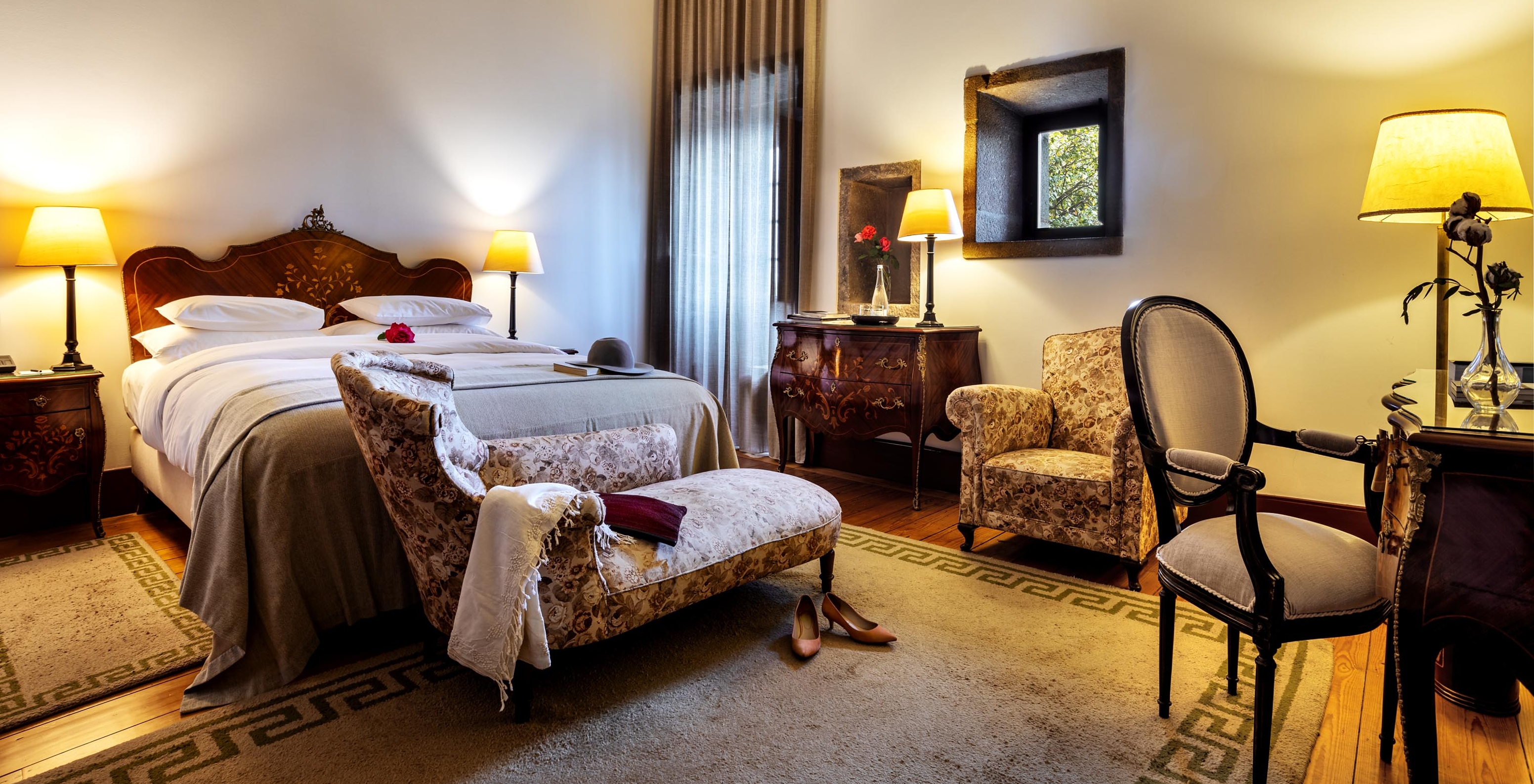 The Standard Suite of The Pousada Mosteiro Guimarães has a double bed with a chaise longue at the foot and an armchair