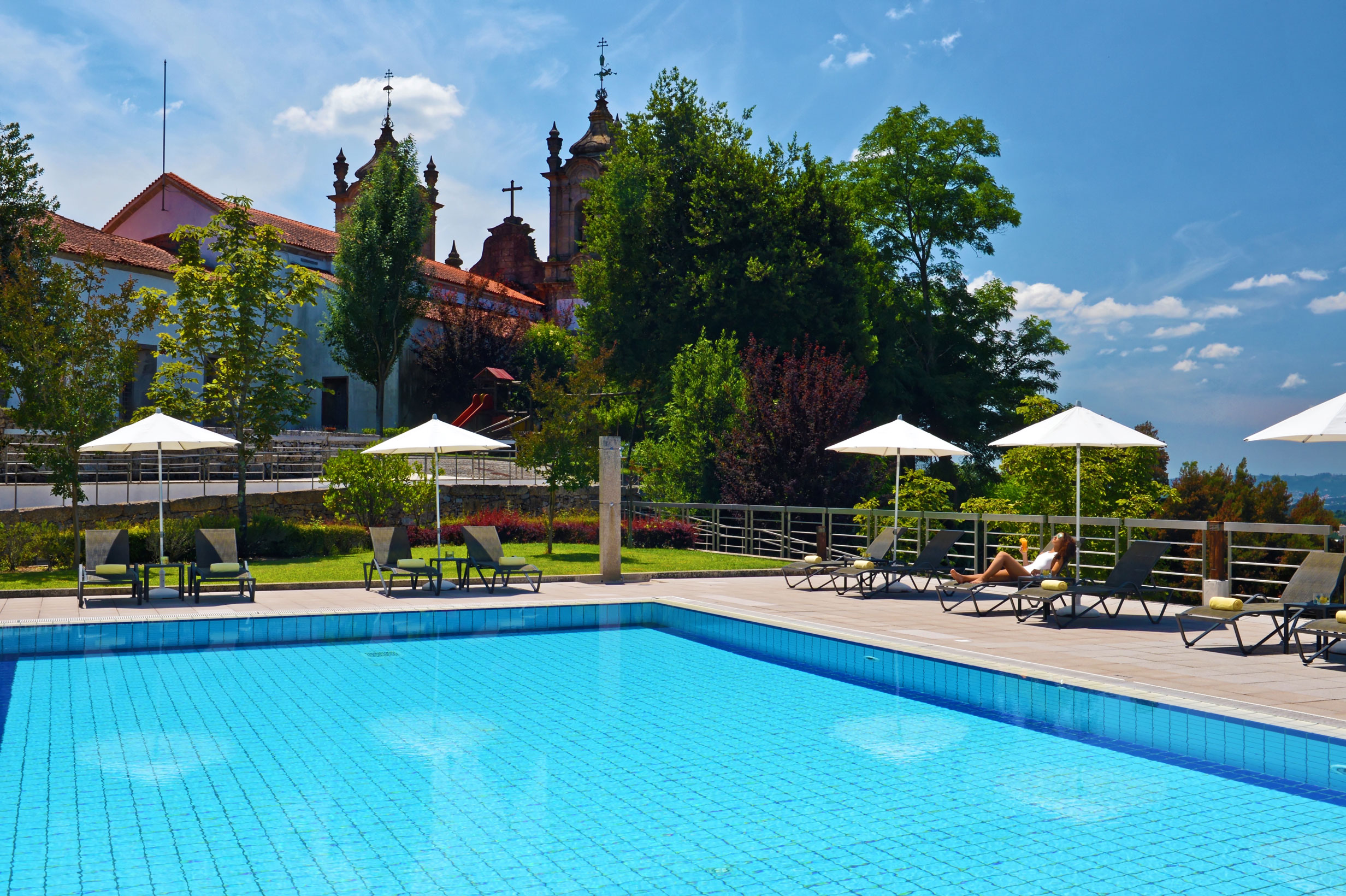 The Pousada Mosteiro Guimarães has an outdoor pool with sun loungers and umbrellas