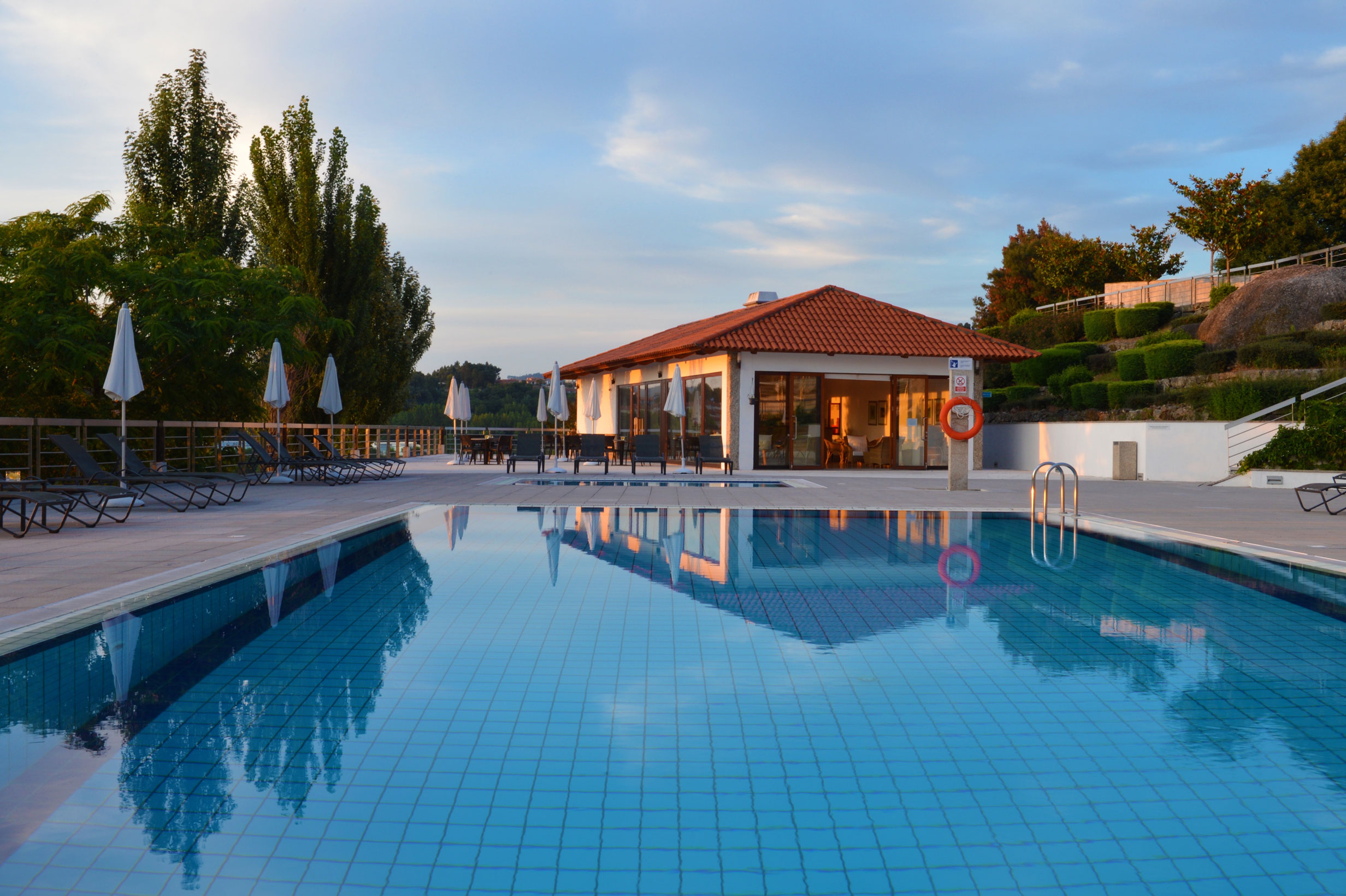 The Pousada Mosteiro Guimarães has an outdoor pool with a house and sun loungers
