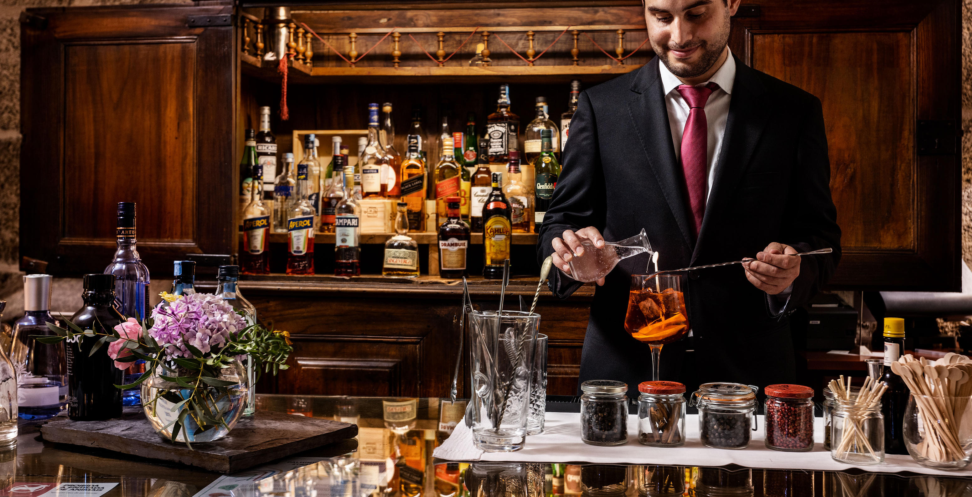 The bar at the Hotel in the Historic Center of Guimarães features a gentleman serving a drink and several displayed bottles