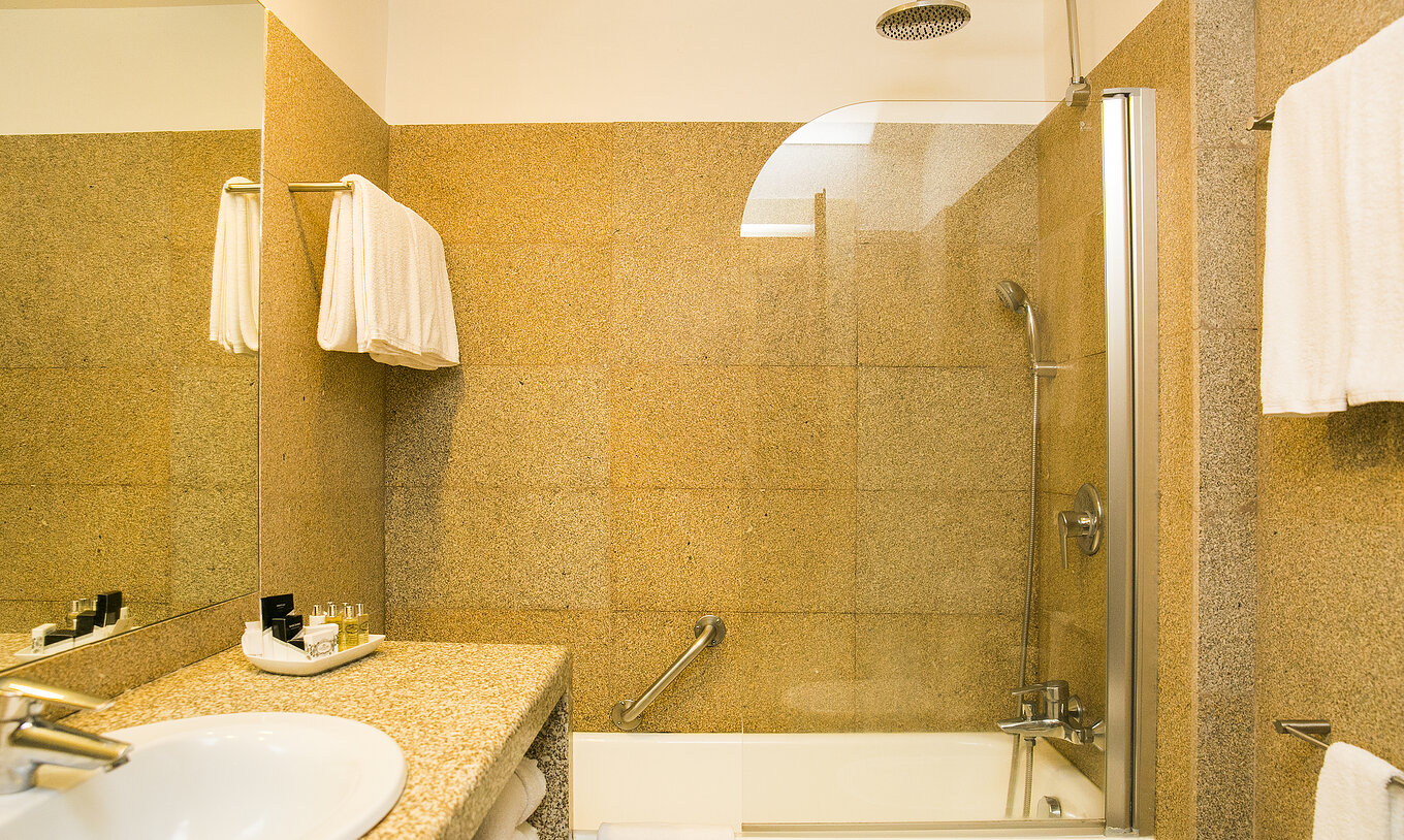 The Classic Room of The Pousada Mosteiro Guimarães has a bathroom with brown tones, a bathtub, and a sink