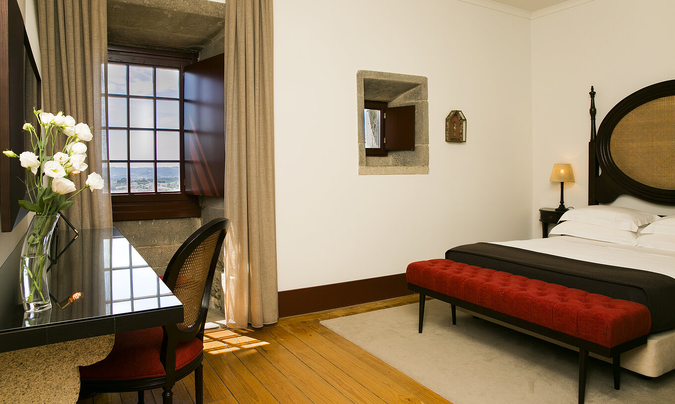 The Historical Superior of The Pousada Mosteiro Guimarães has a double bed with a dark wood and straw headboard