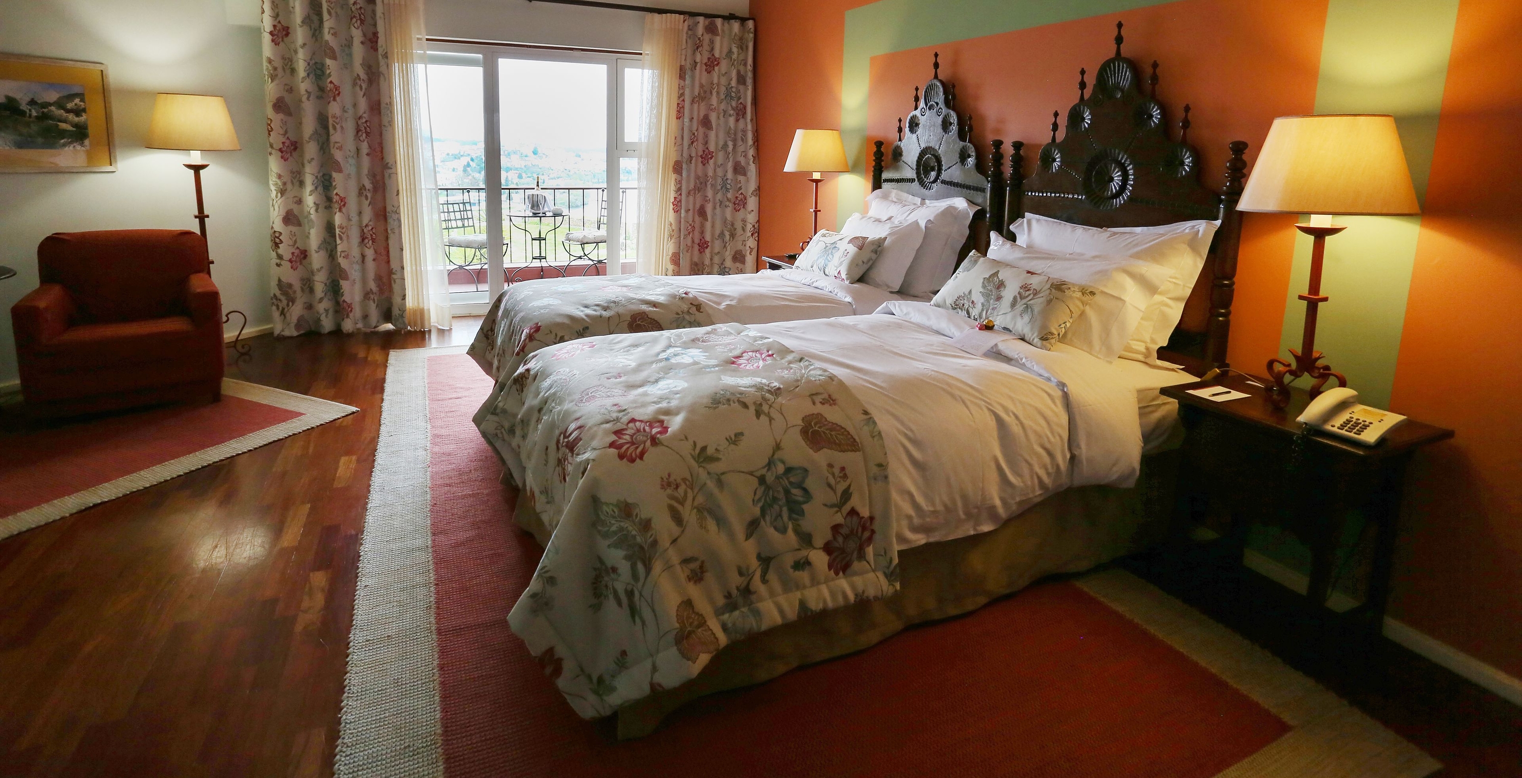 The Large Family Room of The Pousada Valença has two separate beds with a wooden headboard, a balcony, and an armchair 