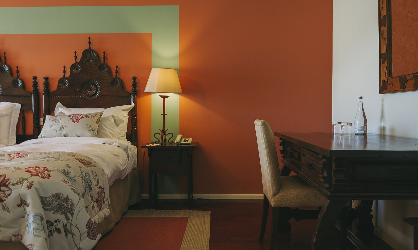 The Classic Room of The Pousada Valença has two separate beds with a wooden headboard and a desk