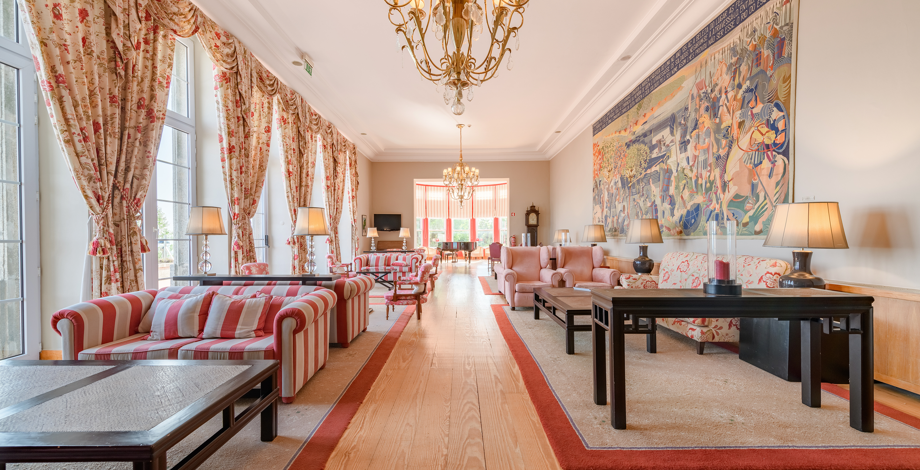 Living room with patterned sofas, side tables, and several windows in the hotel in Monte de Santa Luzia