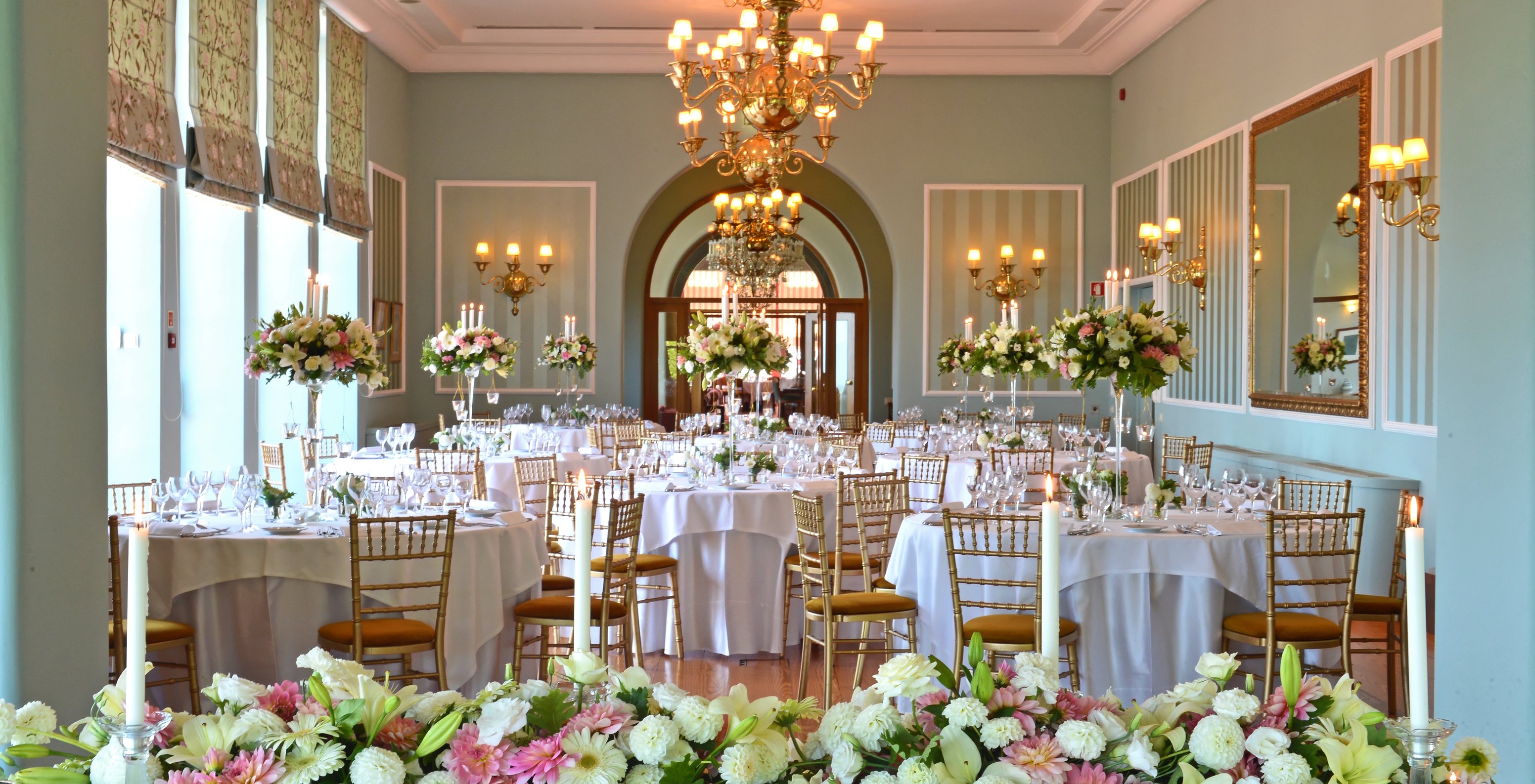 Room decorated for a wedding with round tables and several flower vases in a hotel in Monte de Santa Luzia