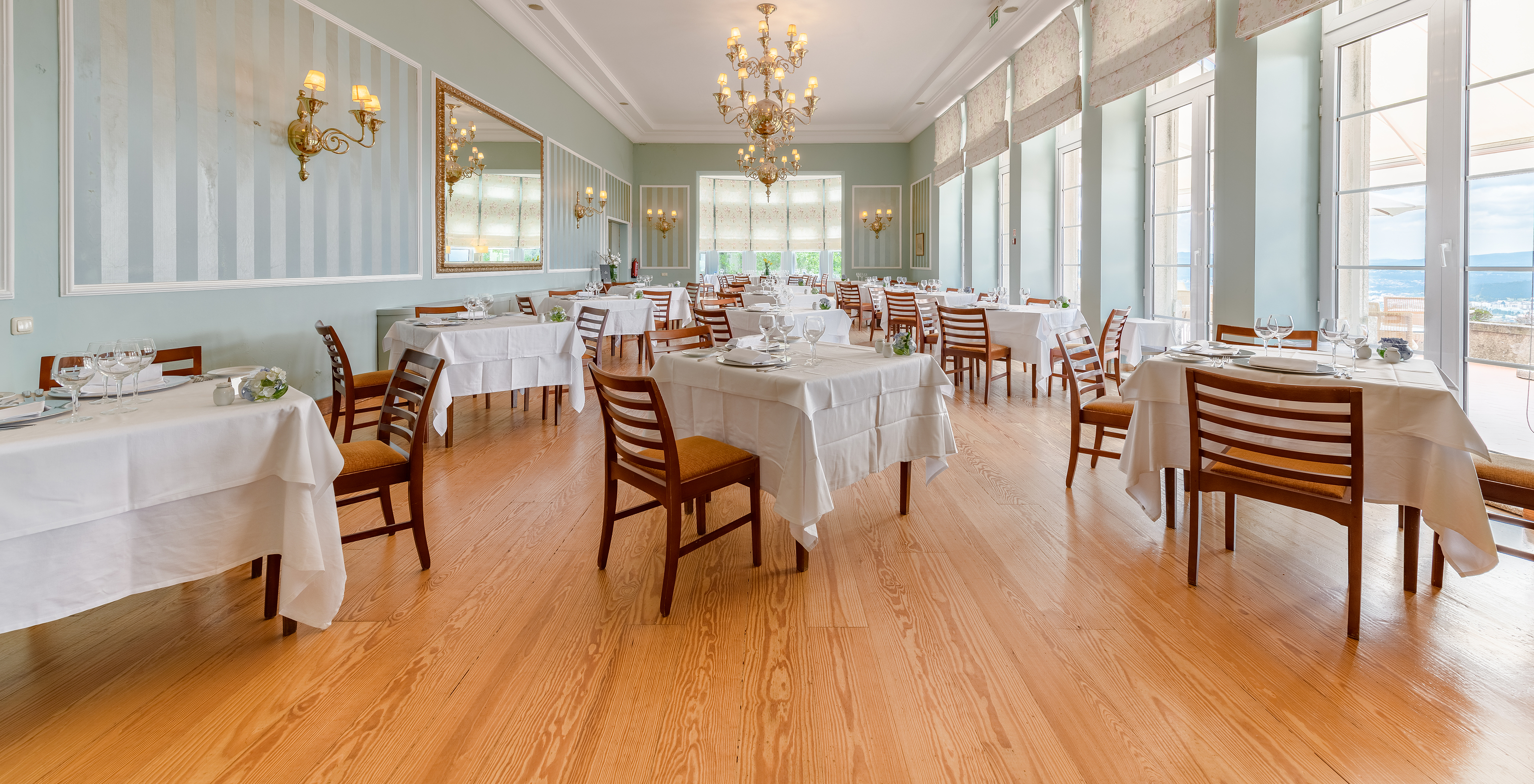The restaurant at the Historic Hotel in Viana do Castelo has several square tables in a room lit by natural light