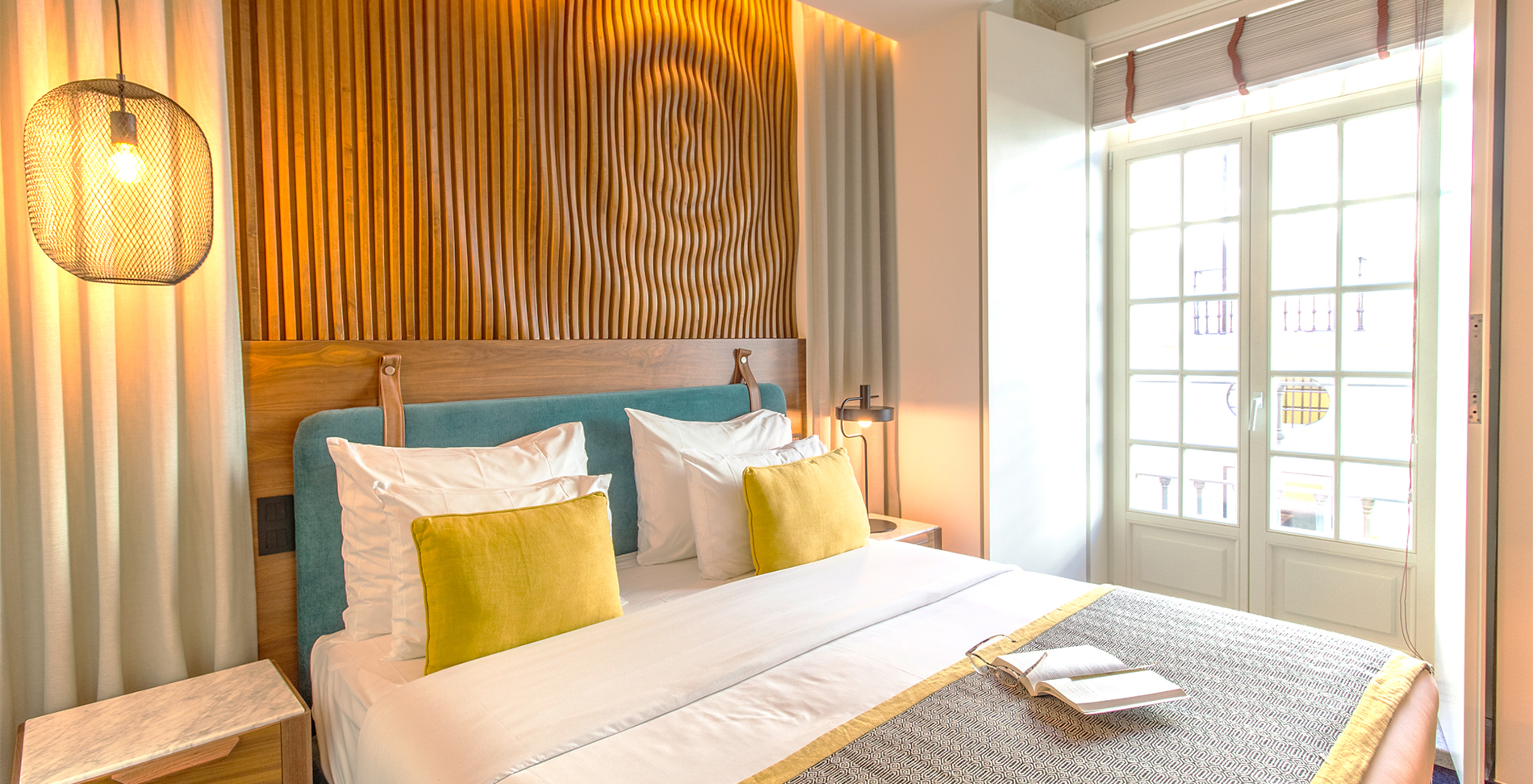 The Deluxe Room of The Porto Inn - Rua das Flores has a turquoise double bed, white sheets, and a wooden headboard