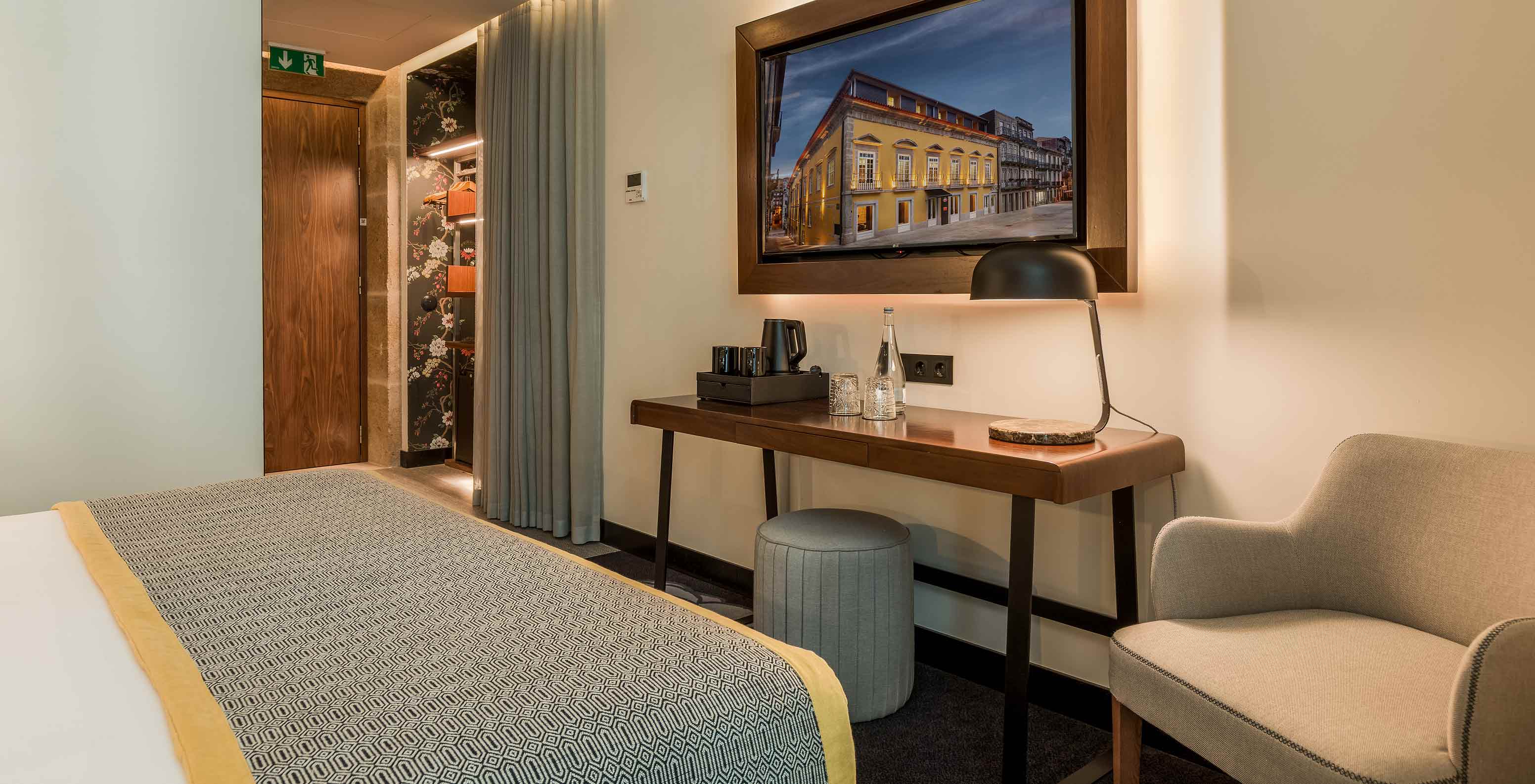 The Deluxe at Pousada Porto - Rua das Flores has a desk and television in front of the bed, an armchair, and a pouf