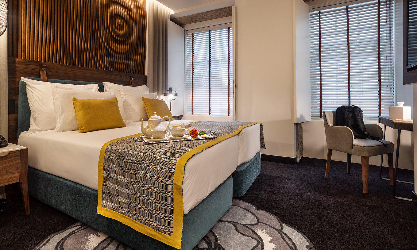 The Classic Room of The Porto Inn - Rua das Flores has a turquoise double bed, white sheets, and a wooden headboard