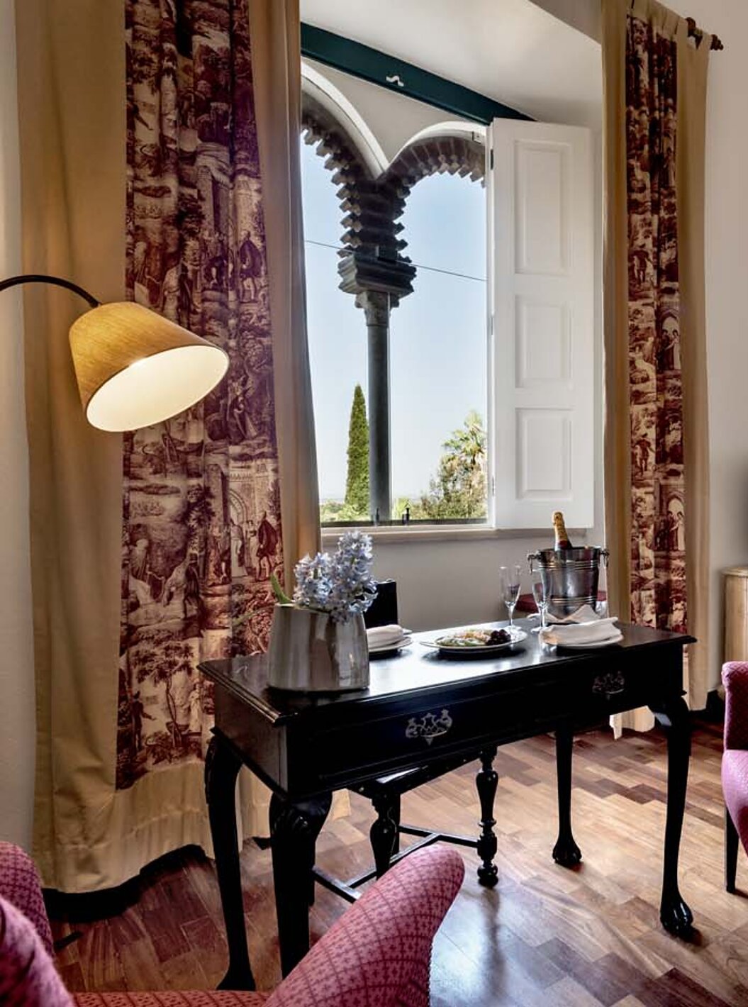 El Suite Especial de la Pousada Castelo Alvito tiene una mesa con una botella de Champagne y una ventana en arcos