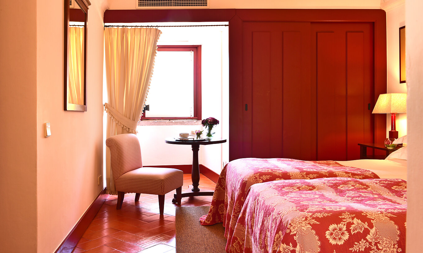 La Habitación Clásica de la Pousada Convento Beja tiene una mesa de apoyo con una silla, junto a la ventana dLa Habitación