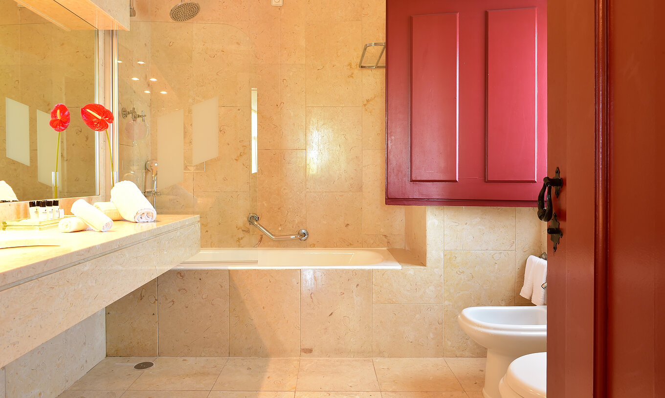 La Junior Suite de la Pousada Convento Beja tiene una bañera con ducha y una flor decorativa junto al lavabo