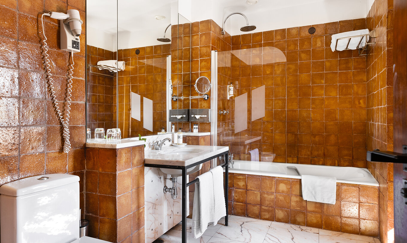 La suite de la Pousada Convento Vila Viçosa tiene baño con bañera, lavabo, espejo, toallas y secador de pelo