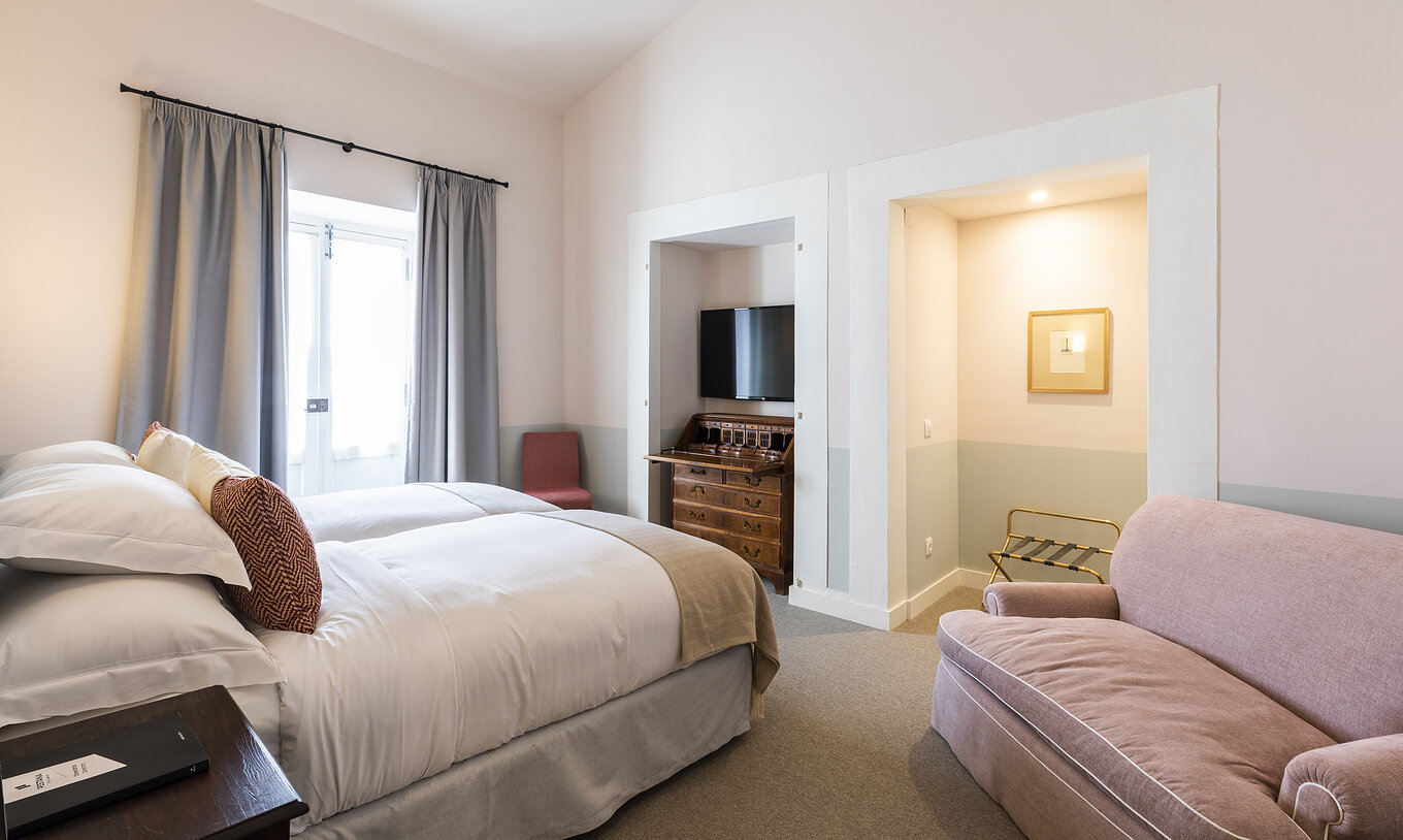 El Cuarto Premium de la Pousada Vila Óbidos tiene dos camas con televisión frente a ellas, ventana y sofá cómodo