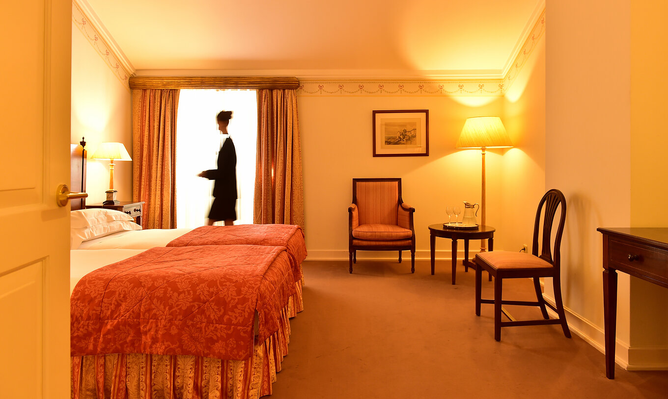 En la Habitación Clásica de la Pousada Palácio Queluz, una mujer prepara el cuarto para recibir a los próximos huéspedes