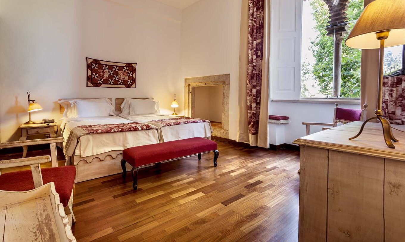 El Quarto Clássico de la Pousada Castelo Alvito tiene dos camas, dos mesas de noche y un banco al fondo de la cama