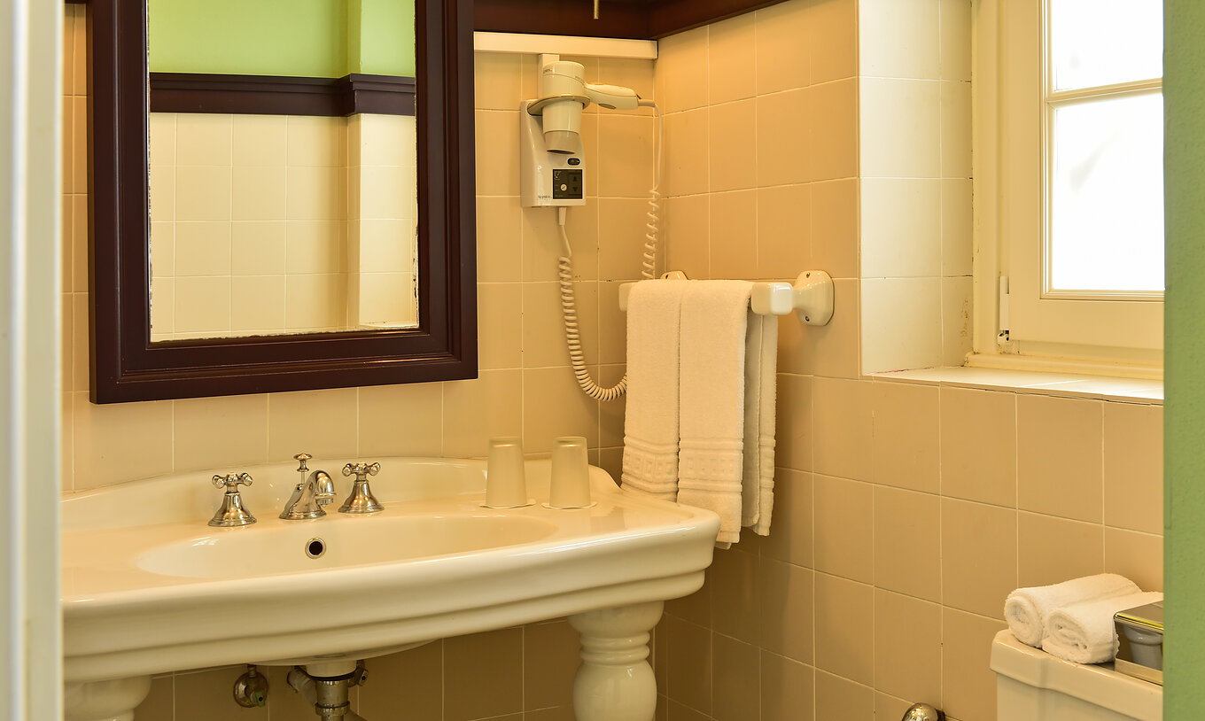 El Cuarto Clásico de la Pousada Convento Évora cuenta con un baño con lavabo y un espejo con marco de madera