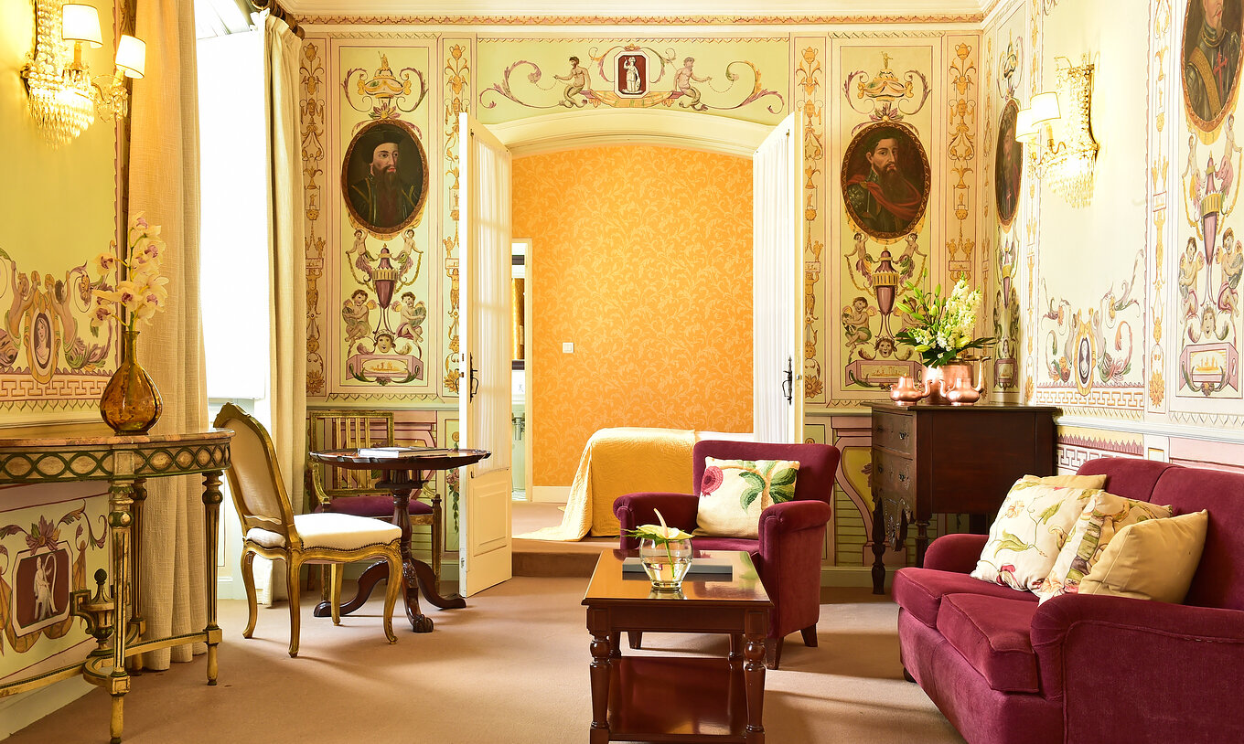 La Suite Especial de la Pousada Convento Évora cuenta con una sala de estar con sofá y un sillón y una cama al fondo