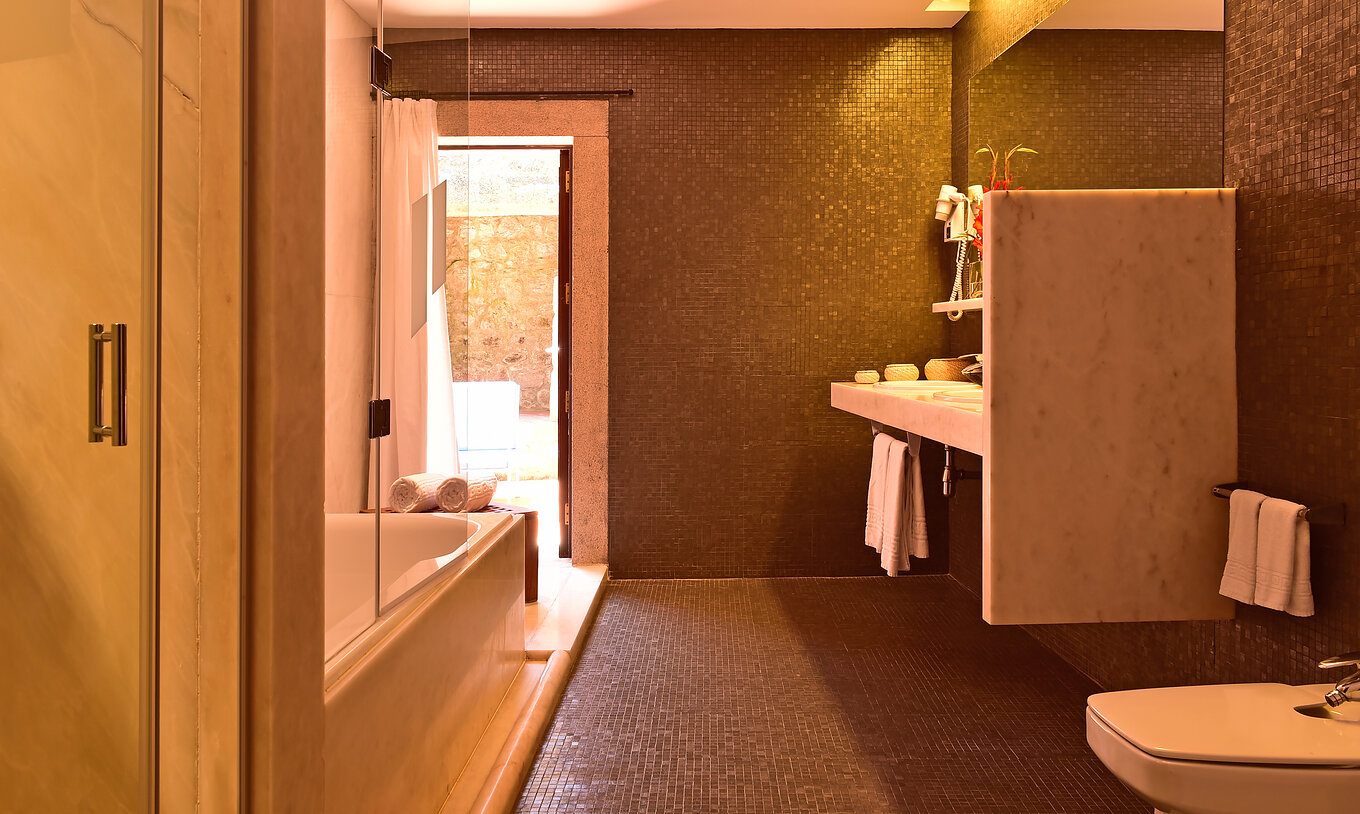 La Master Suite de la Pousada Mosteiro Crato tiene un baño en baldosas negras con bañera, bidet y dos lavabos