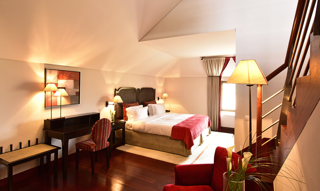 La Suite Standard de la Pousada Convento Tavira tiene un cuarto con cama y escritorio y unas escaleras a la sala de estar