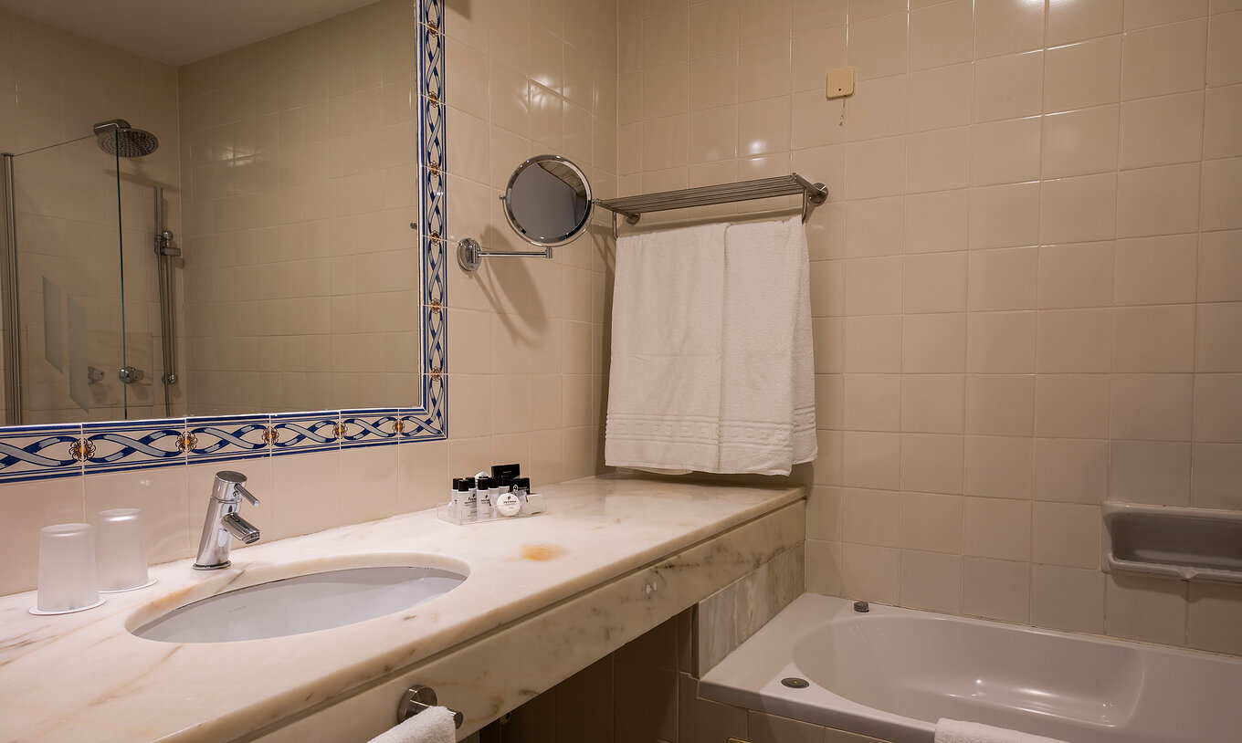 El Cuarto Superior Vista Mar de la Pousada Sagres cuenta con un baño con lavabo con amenities, toallas y bañera