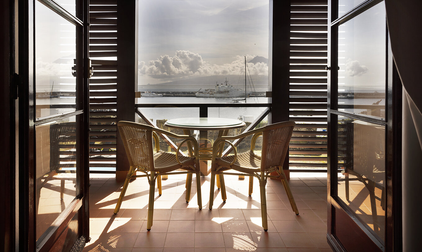 El Cuarto Superior Familiar de la Pousada Forte Horta tiene un balcón con mesa y sillas y vista al mar