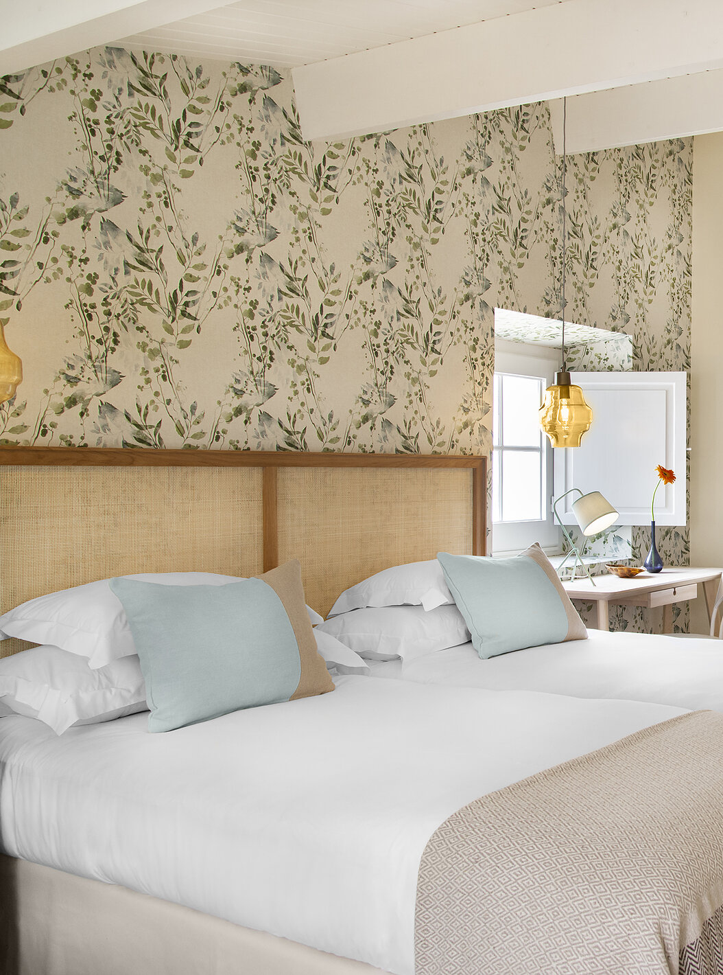 La Habitación Familiar Casa Lidador - Óbidos tiene dos camas individuales, papel tapiz floral, ventana y espejo en la pared