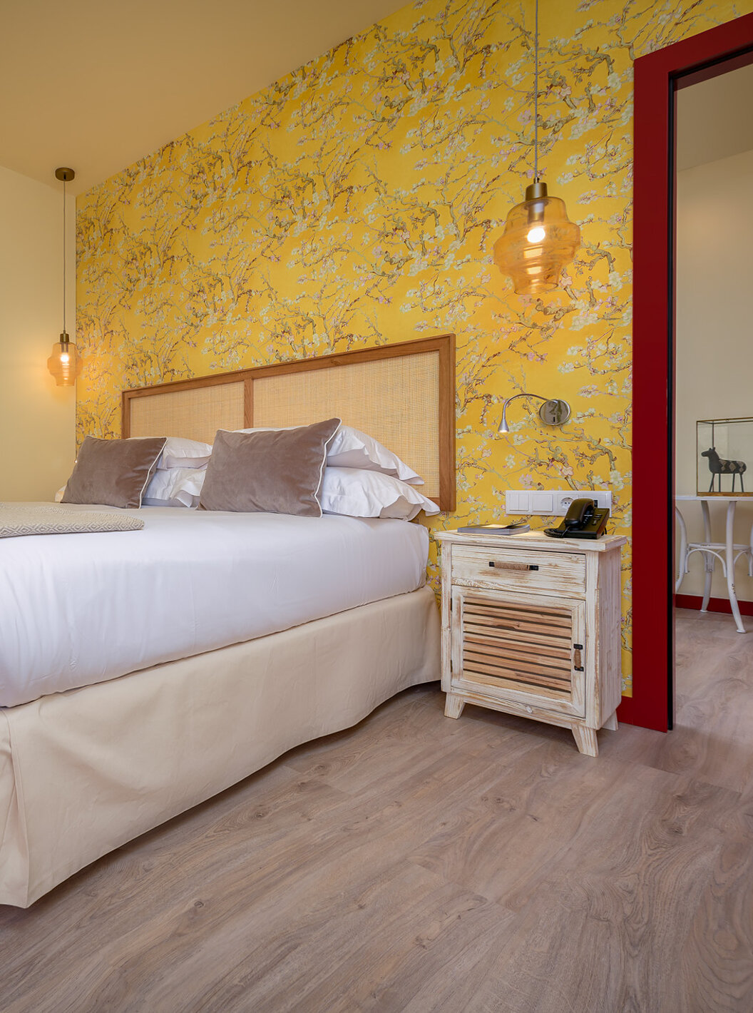 La Suite Casa Lidador - Óbidos tiene cama matrimonial, papel tapiz floral amarillo y una mesita de noche