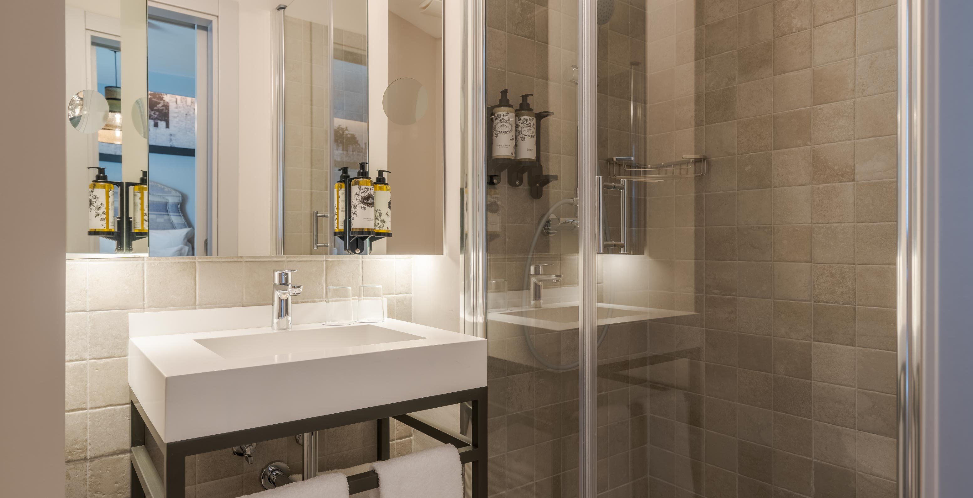 Cozy en Pousada Alfama tiene un baño moderno con ducha, lavabo blanco, toallas blancas y espejo