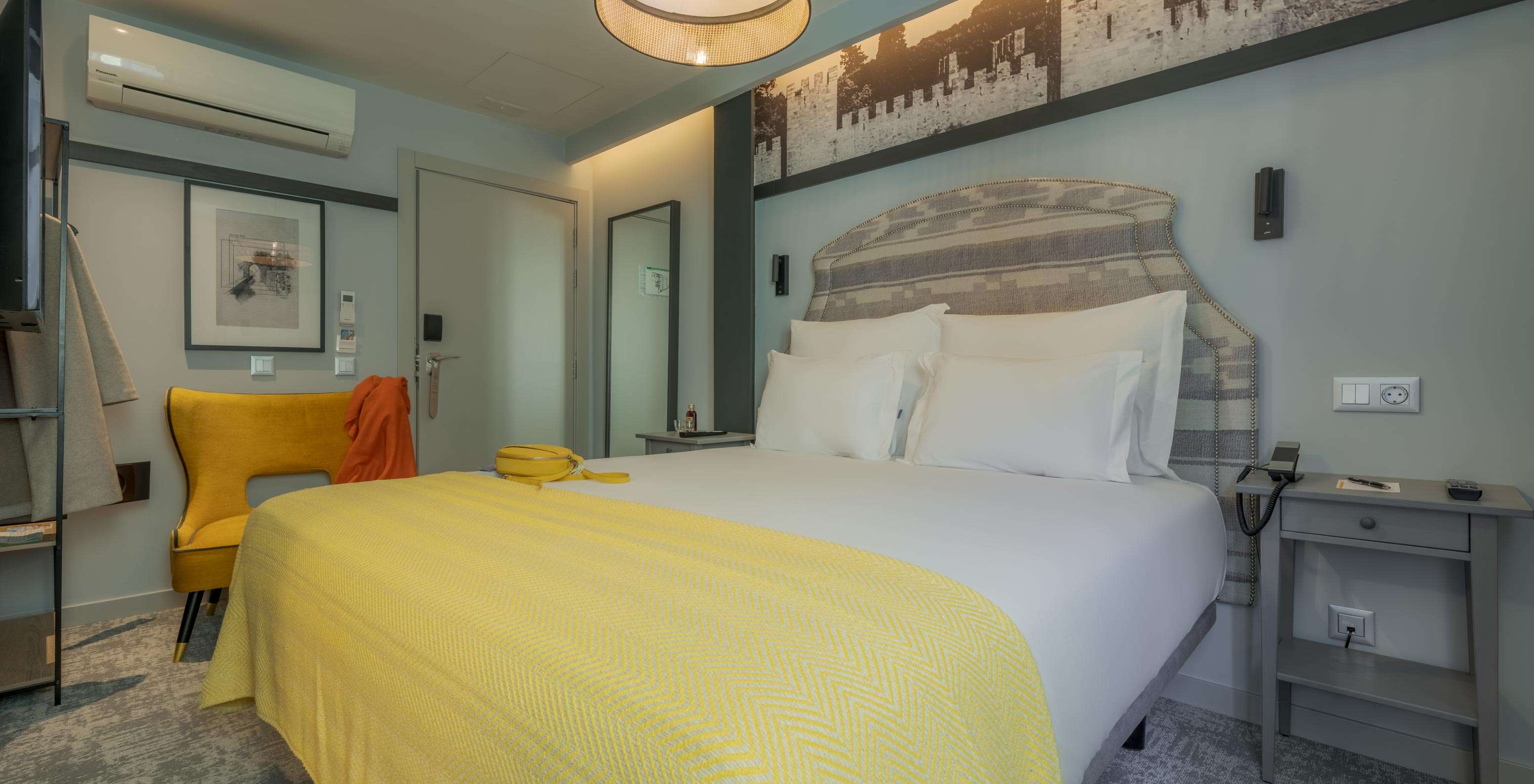 Cozy en Pousada Alfama tiene una cama doble con sábanas blancas, una manta amarilla y un sillón amarillo