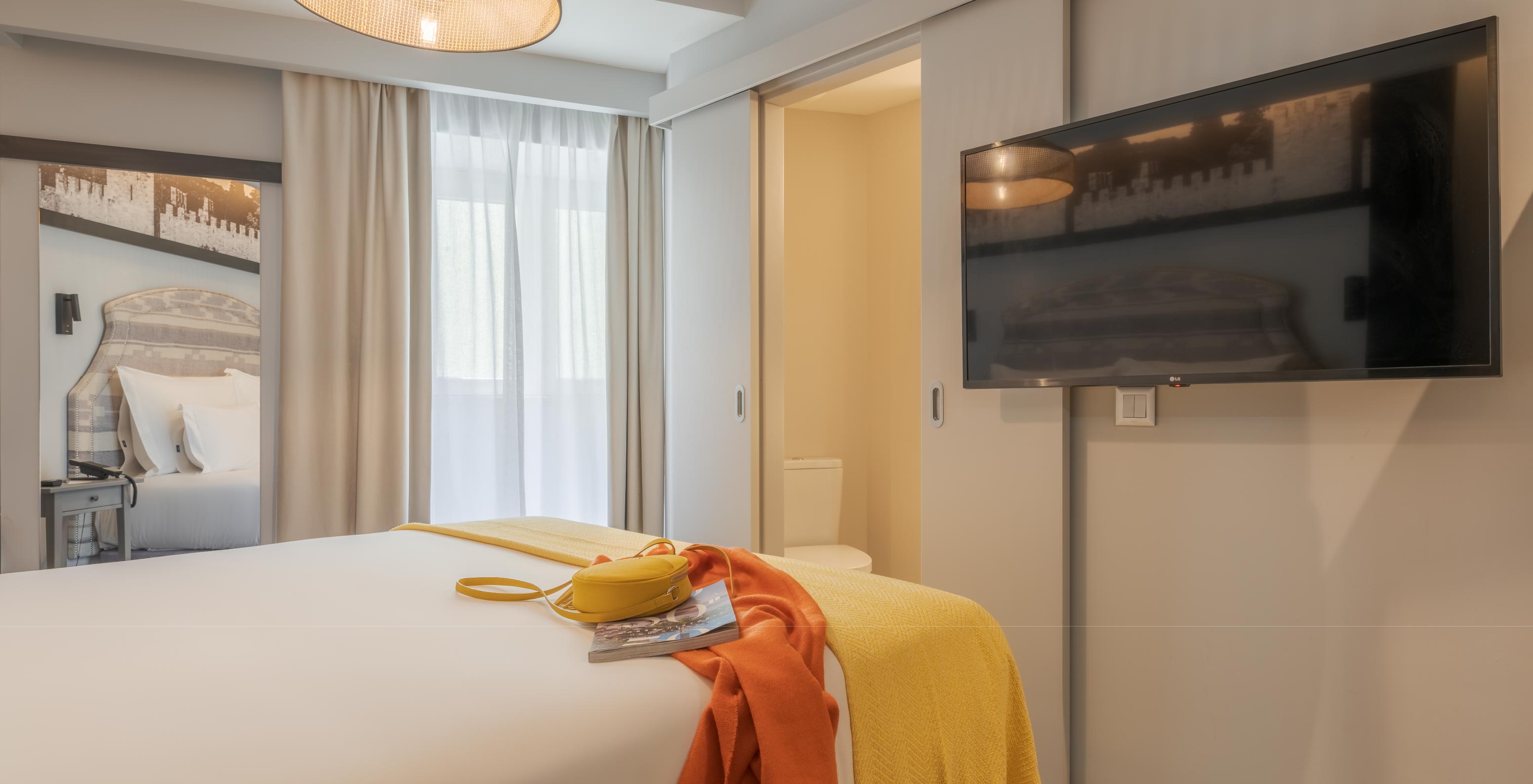 Cozy en Pousada Alfama tiene una cama doble, una ventana con cortinas blancas, un espejo y una TV