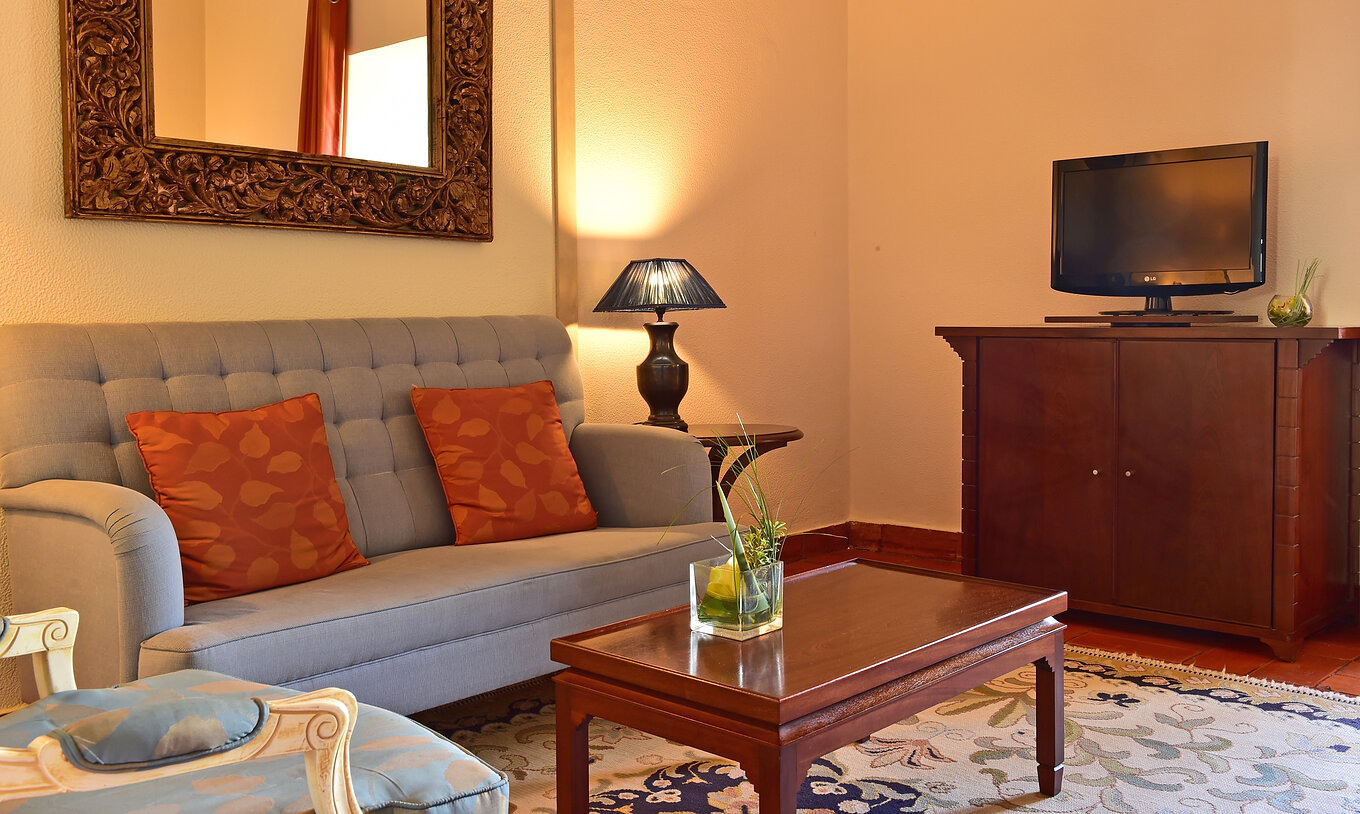 La Suite Standard de la Pousada Castelo Palmela tiene una sala con sofá gris, una mesa de madera en La centro y televisión