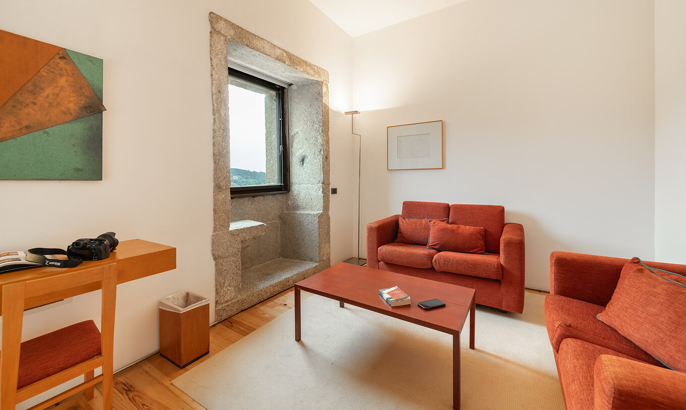 La Suite Standard de la Pousada Mosteiro Amares tiene una sala de estar con sofás rojos y una ventana