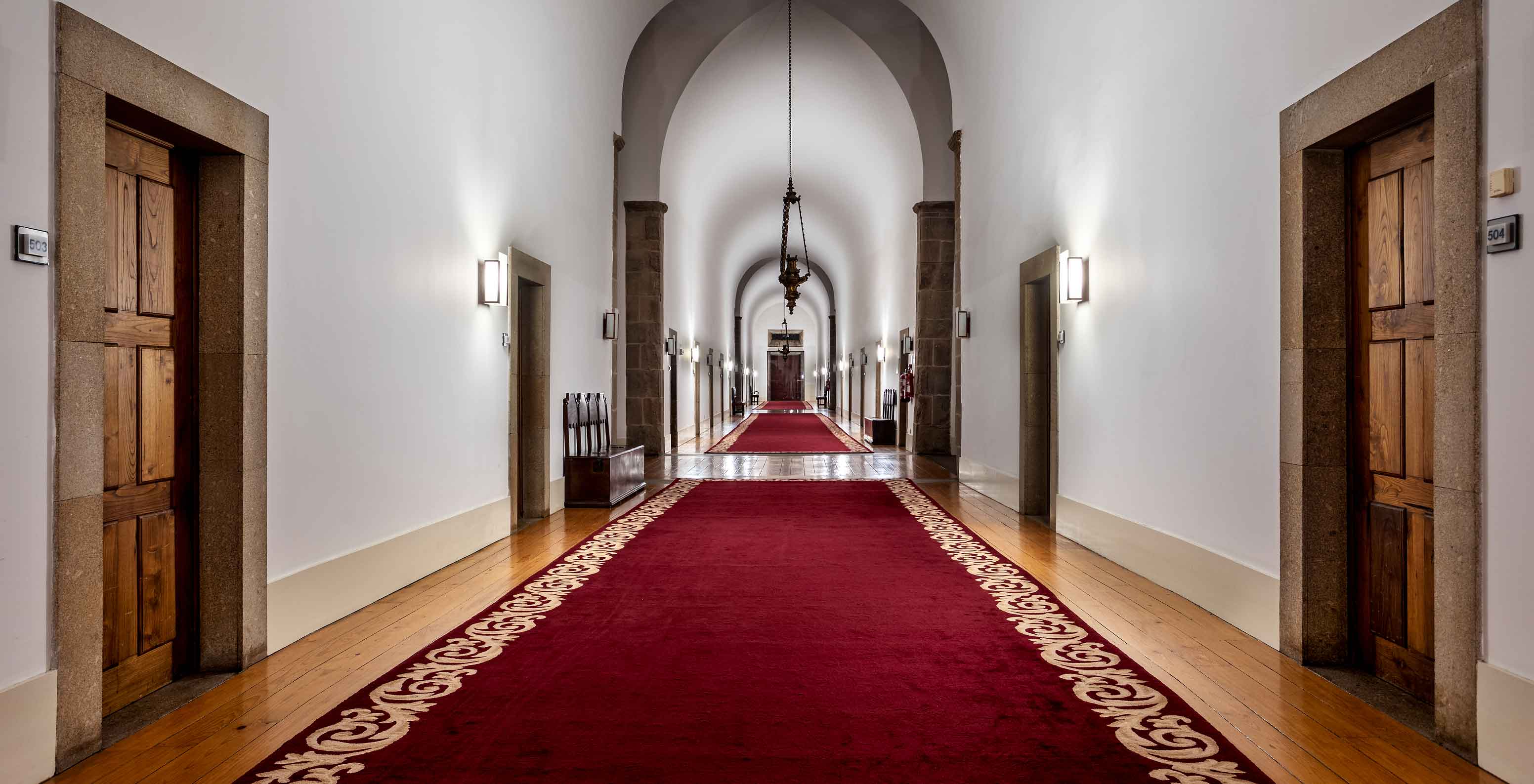 Pasillo con alfombras rojas en la Pousada Mosteiro de Guimarães, un hotel en Guimarães con piscina