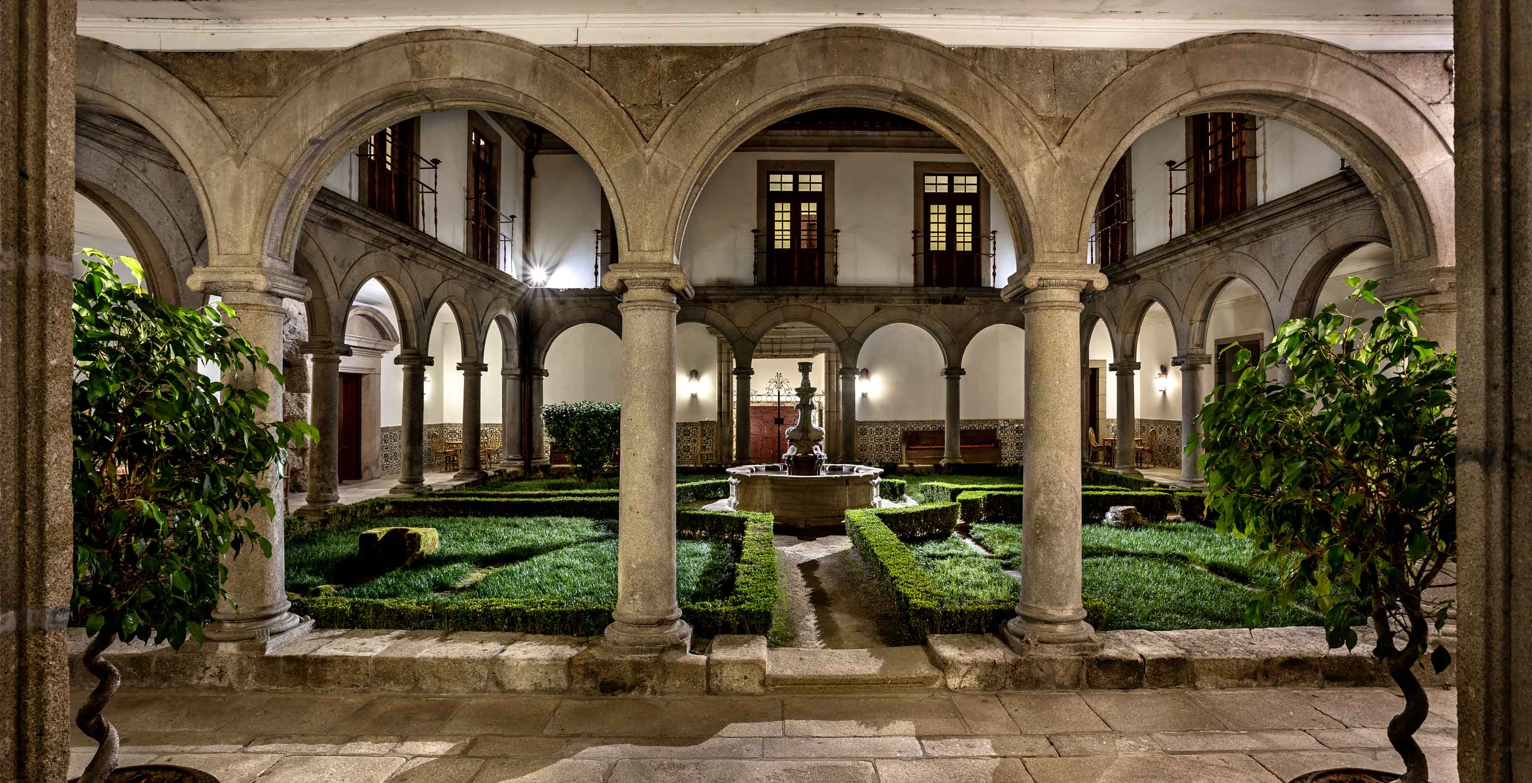 Jardín interior de la Pousada Mosteiro de Guimarães, rodeado de claustros con una fuente en el centro