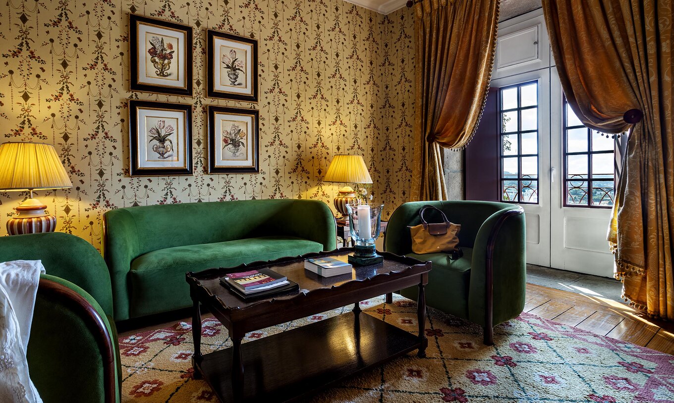 La Master Suite de la Pousada Mosteiro Guimarães tiene una zona de estar con sofás verdes, una ventana alta y cuadros