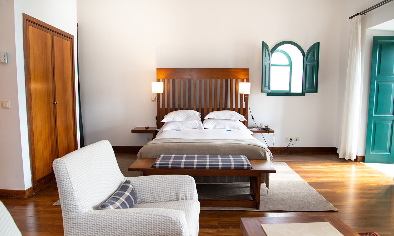 La Suite Spéciale de la Pousada Castelo Alcácer do Sal a un lit double avec une couette beige, un placard et un fauteuil