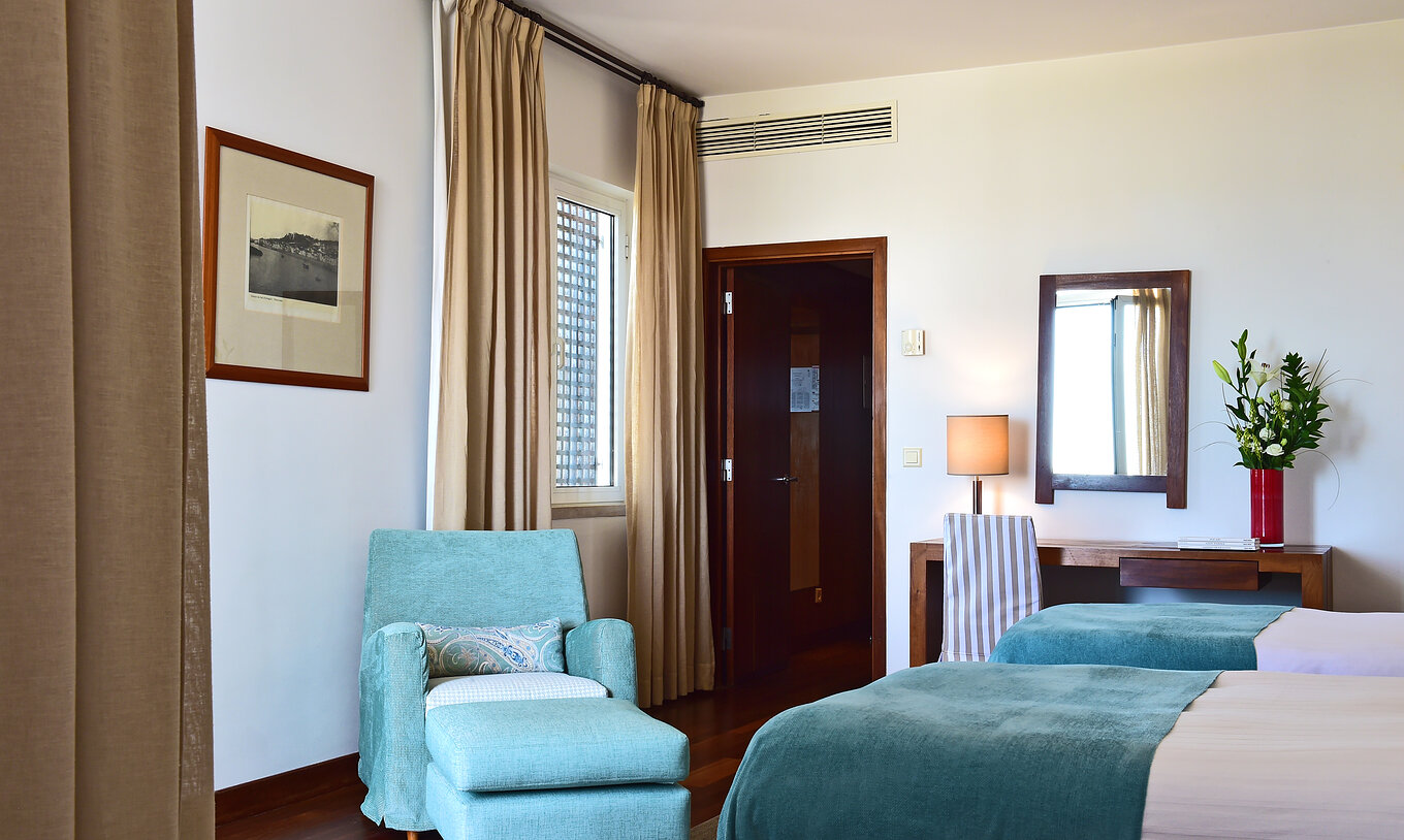 Le Supérieur Familial de la Pousada Castelo Alcácer do Sal a deux lits séparés, avec une couette bleue et un fauteuil